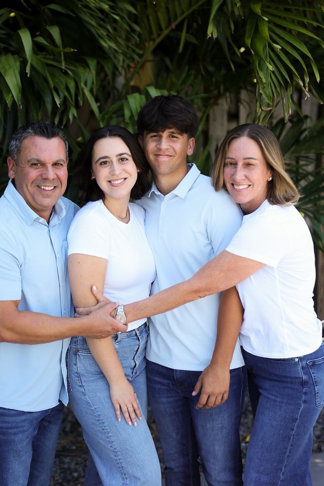 A family is posing for a picture together in front of a palm tree.