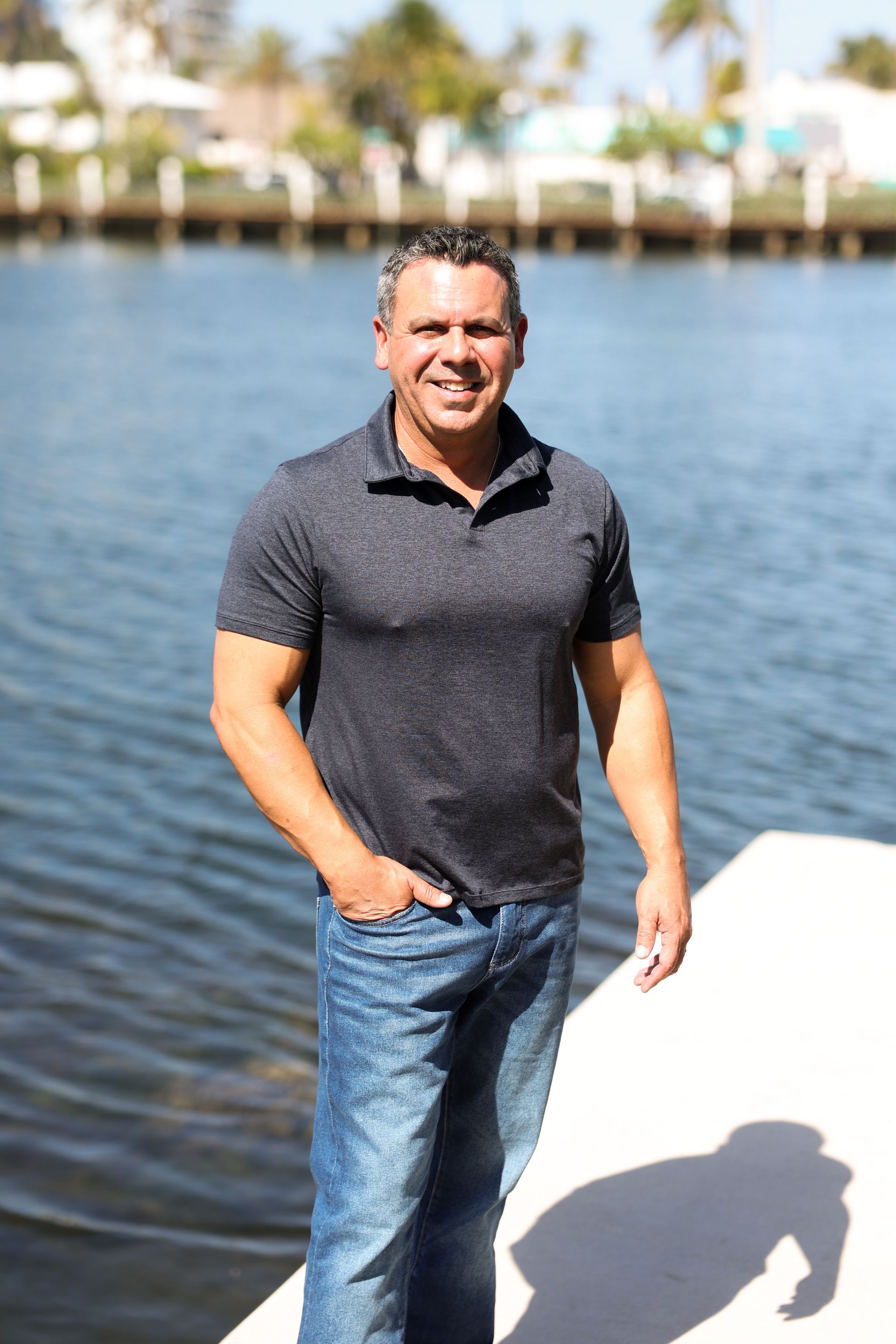 A man is standing on a dock next to a body of water.