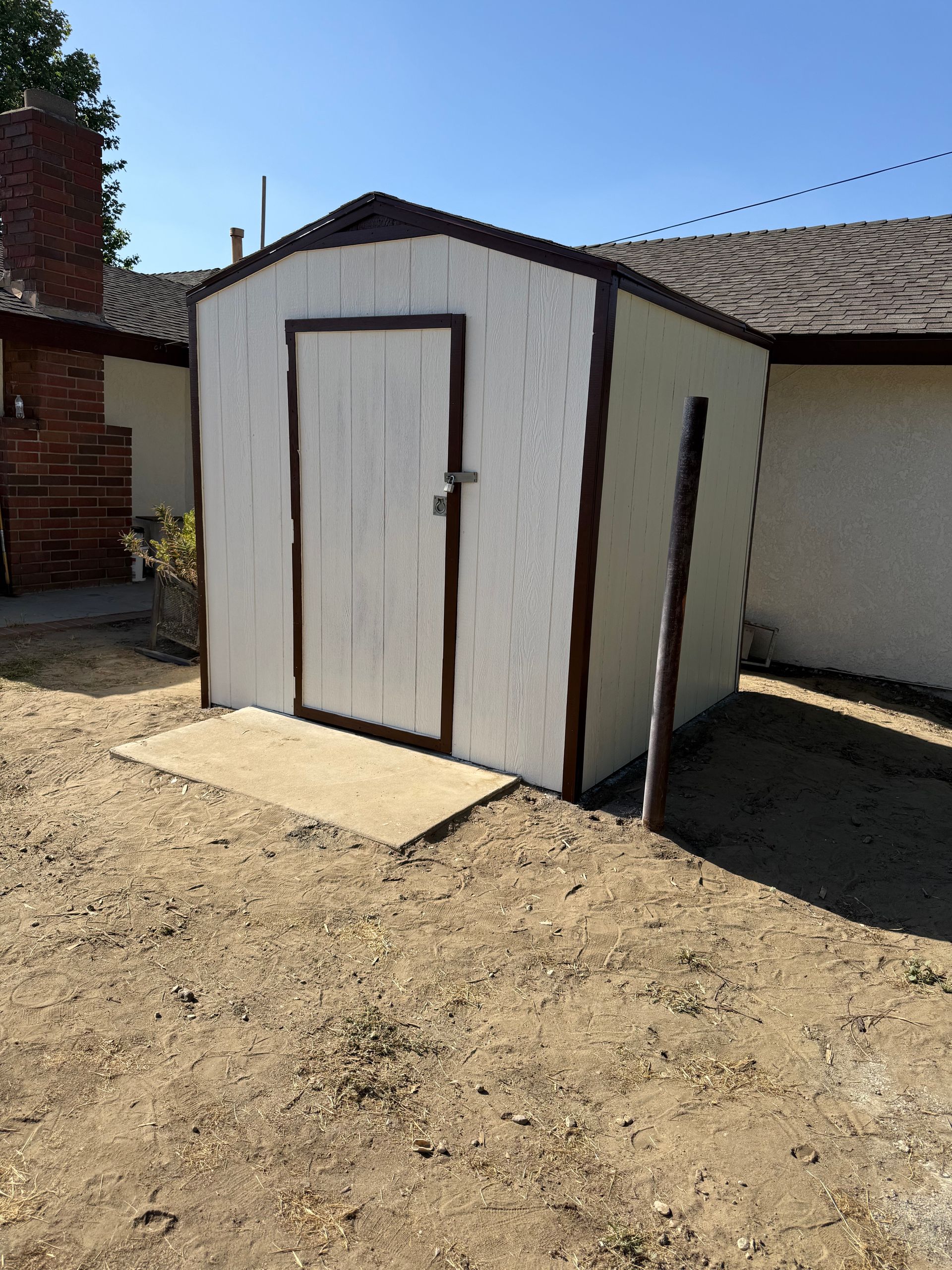 A person is cleaning the side of a house with a high pressure washer.