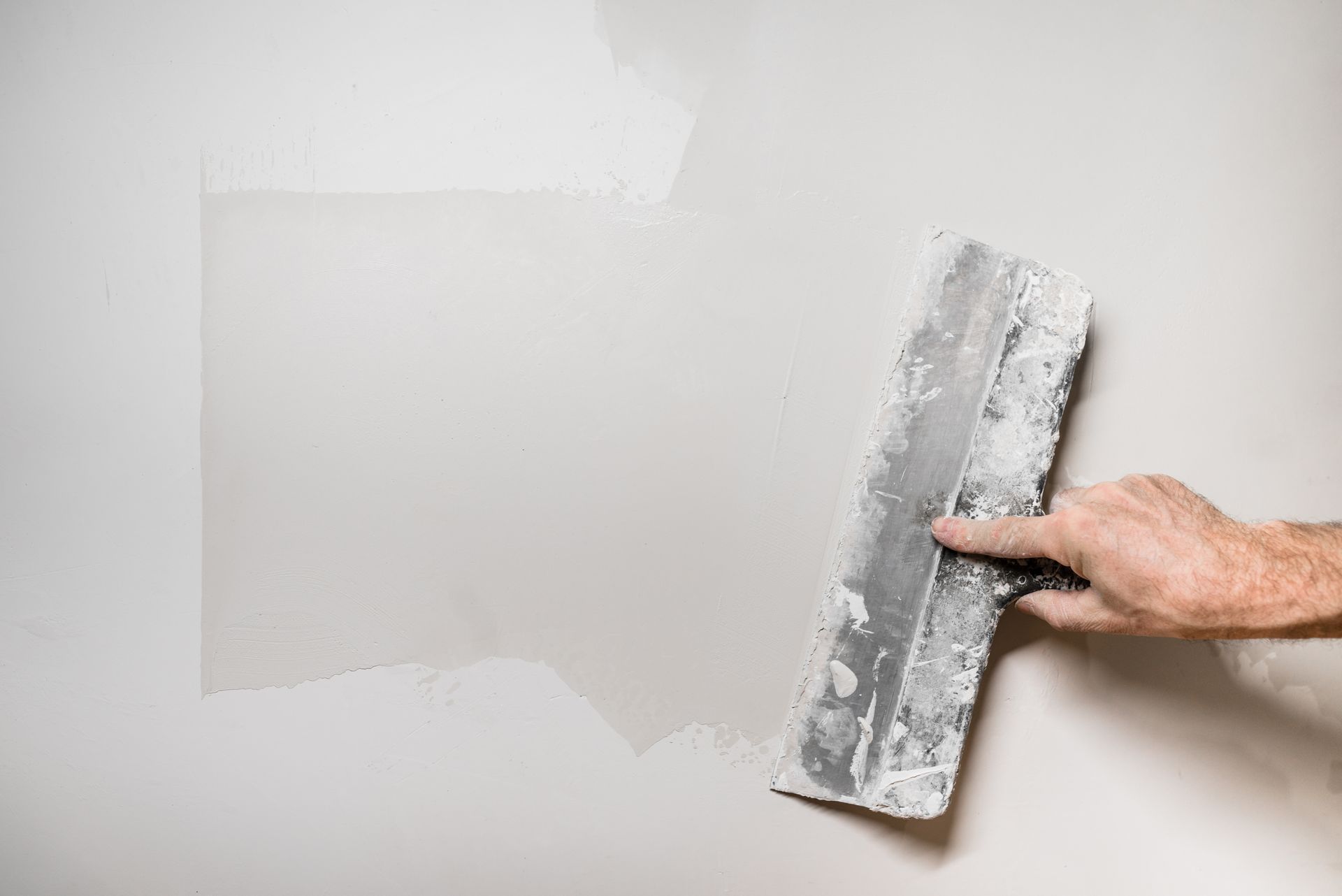 A person is plastering a wall with a trowel.