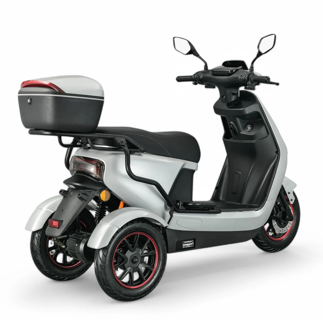 Zilverkleurige driewielige elektrische scooter met zwart zadel, opbergvak en wielen; geïsoleerd op een witte achtergrond.