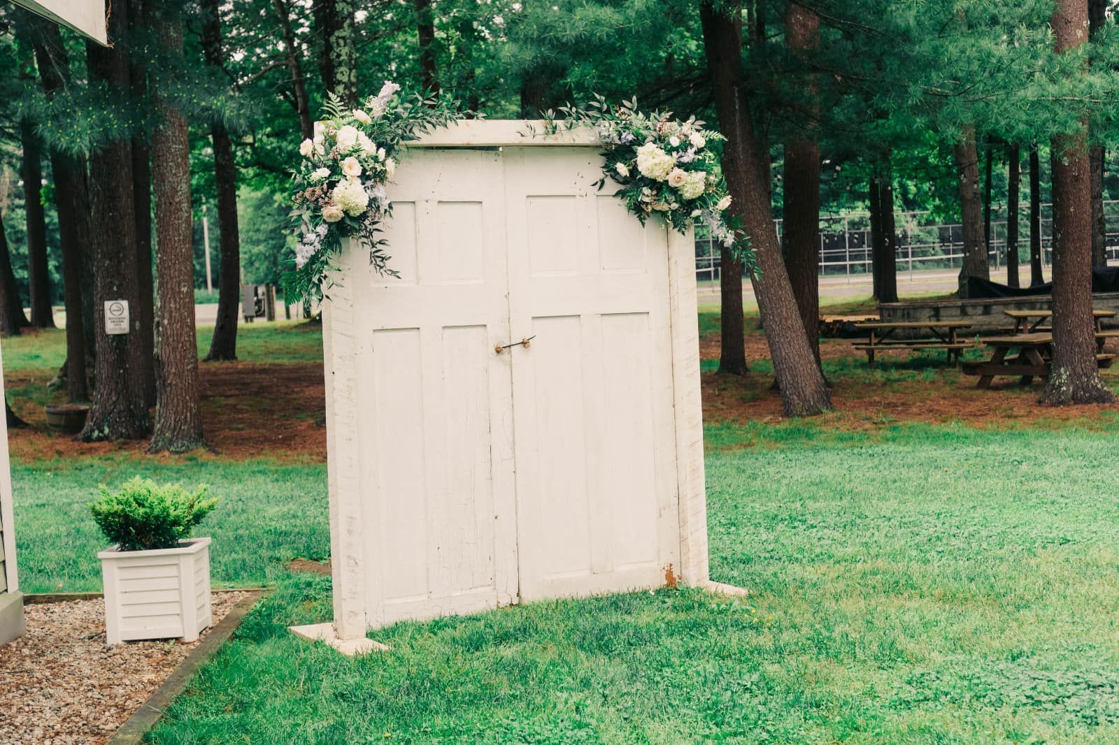 A white door with flowers on it is in the middle of a grassy field.