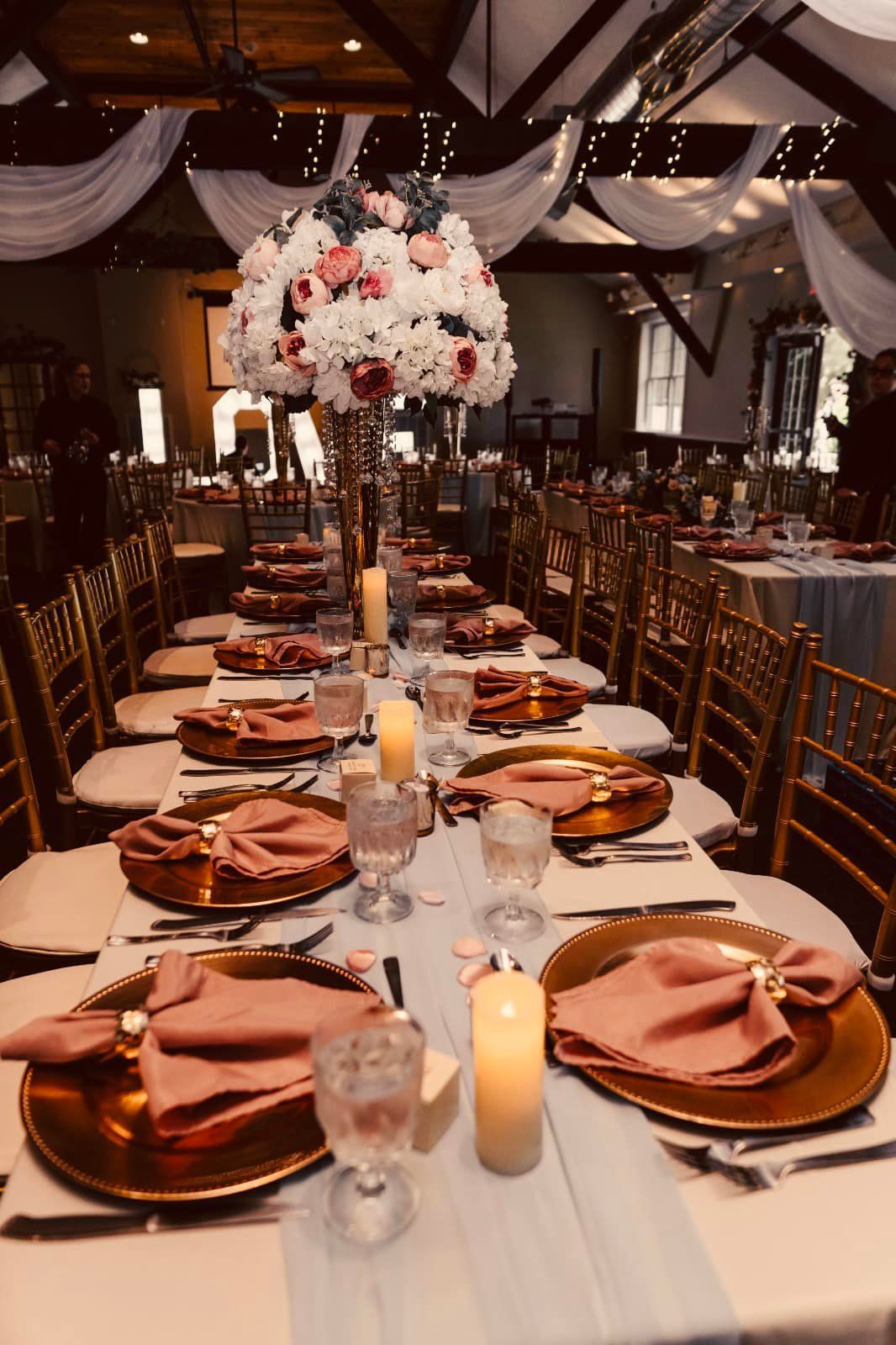 A long table with plates , napkins , candles and a vase of flowers.