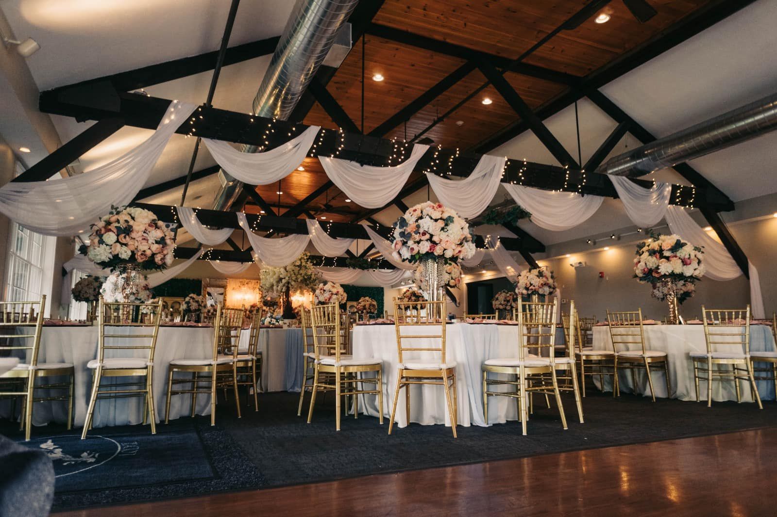 A large room with tables and chairs set up for a wedding reception.