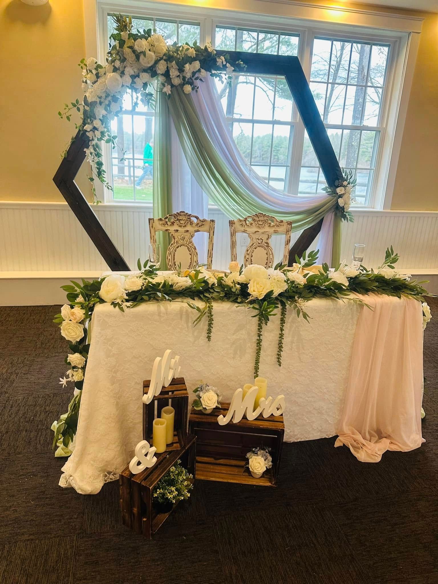 A bride and groom 's table is decorated with flowers and candles.