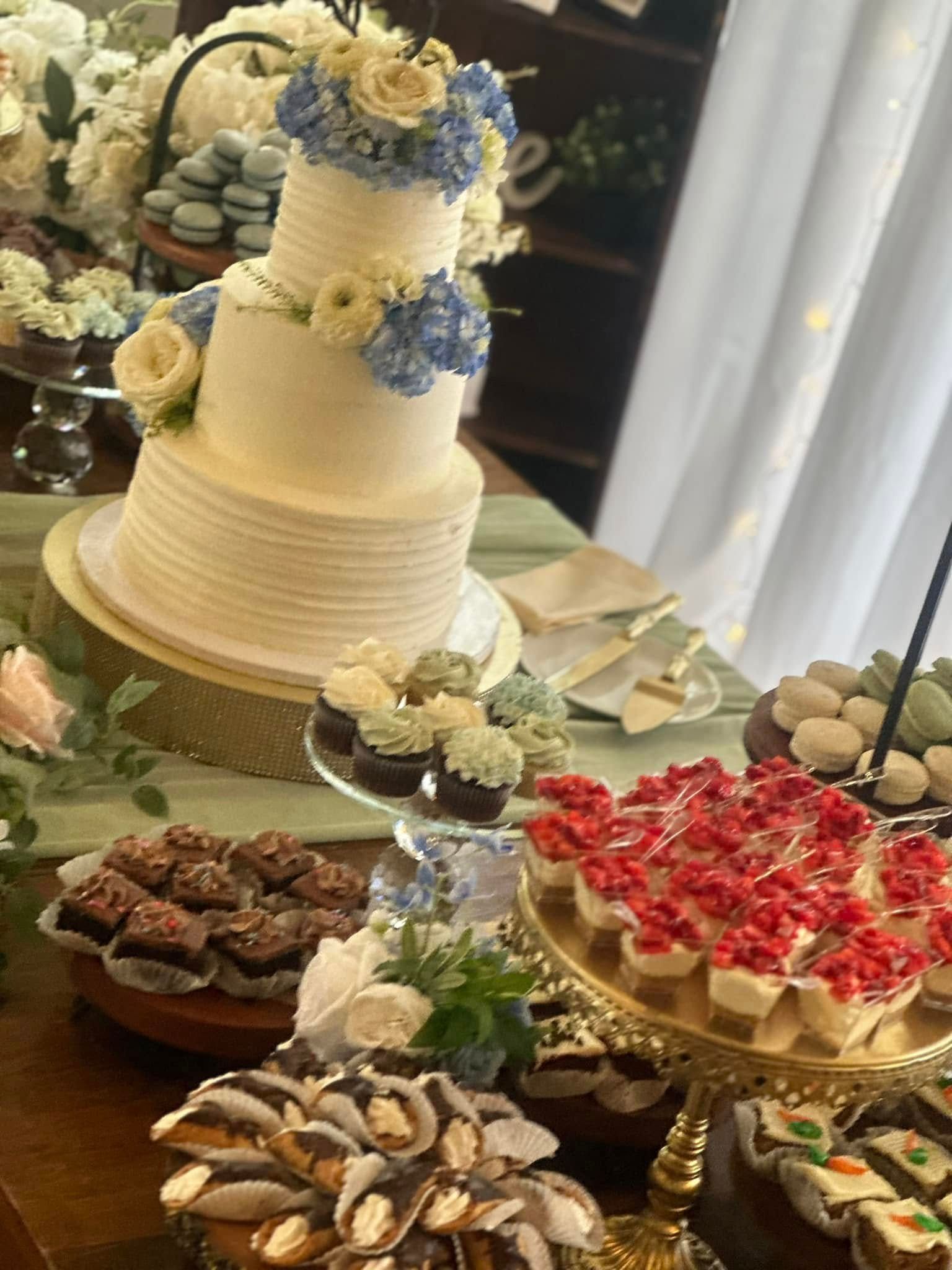 A table topped with a wedding cake , cupcakes , and other desserts.