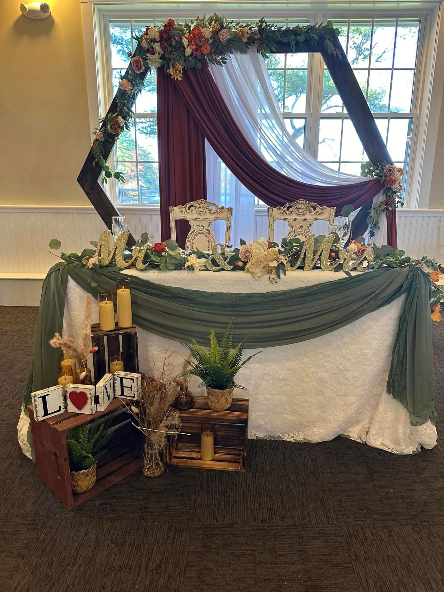 A bride and groom 's table is decorated with flowers and candles in a room.