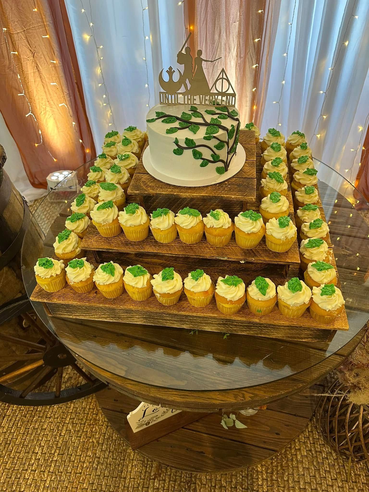 A cake and cupcakes are on a wooden table.