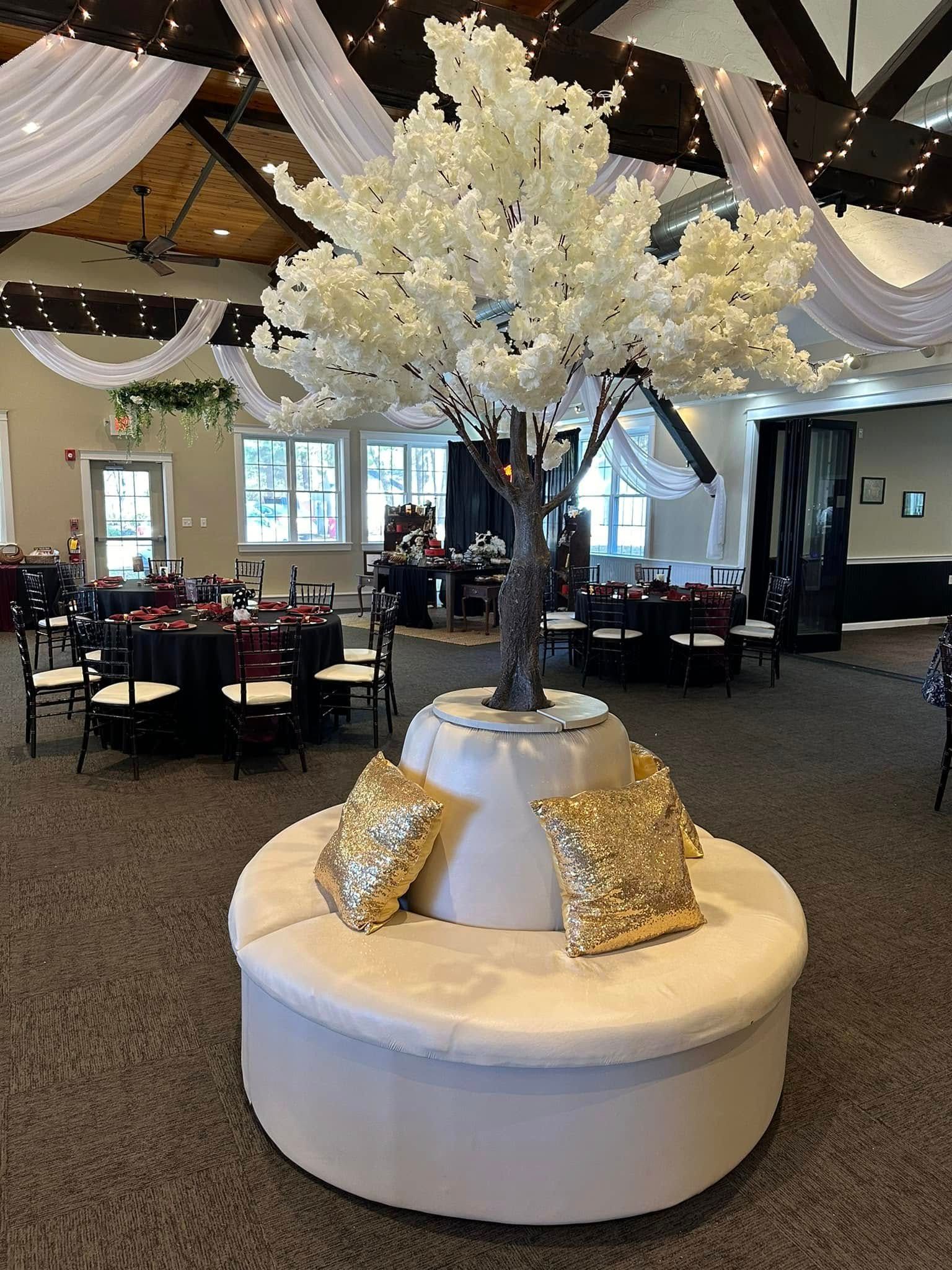 There is a tree in the middle of a room with tables and chairs.
