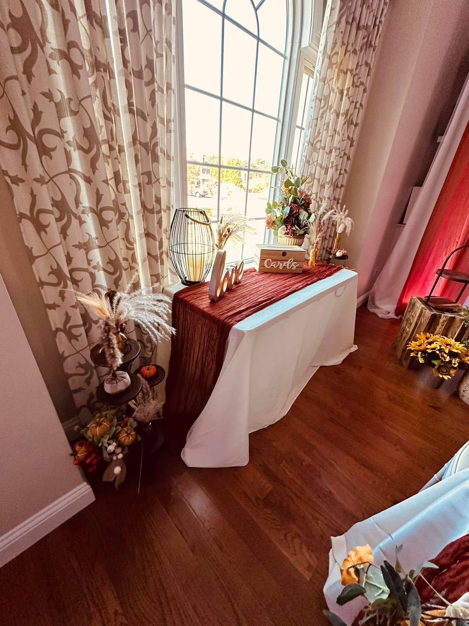 A room with a table and flowers in front of a window.