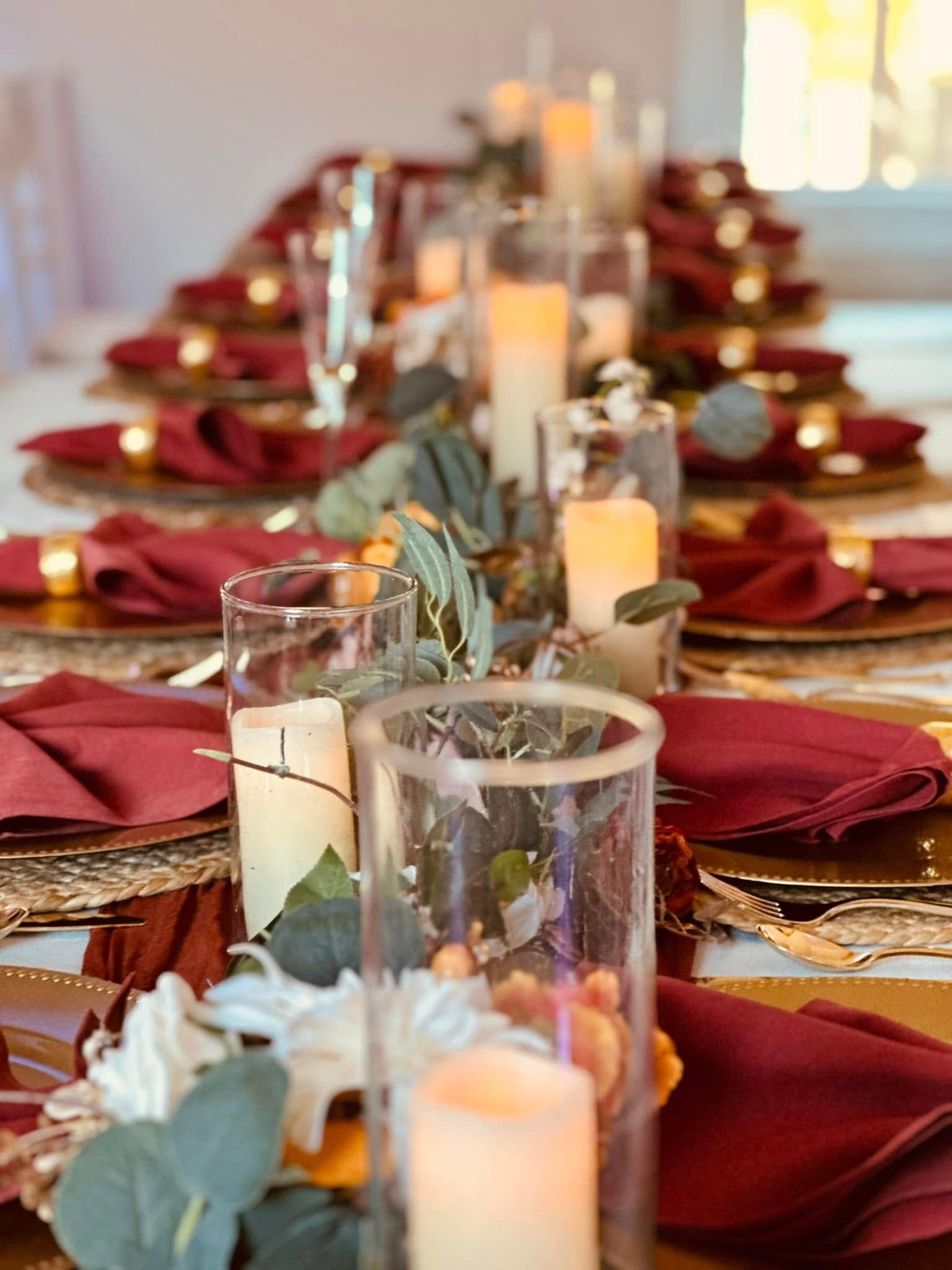 A long table with plates , napkins , candles and flowers on it.