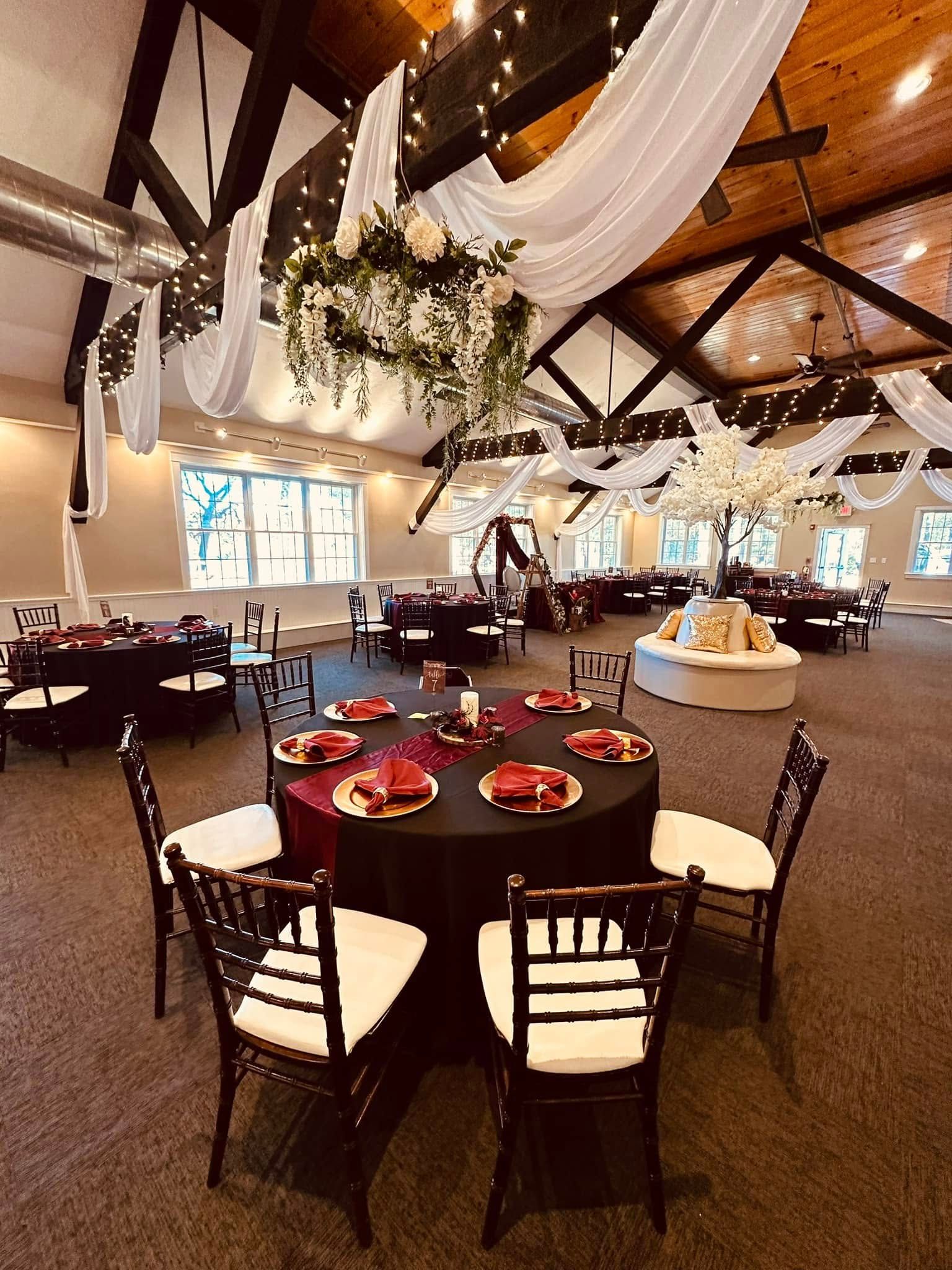 A large room with tables and chairs set up for a wedding reception.