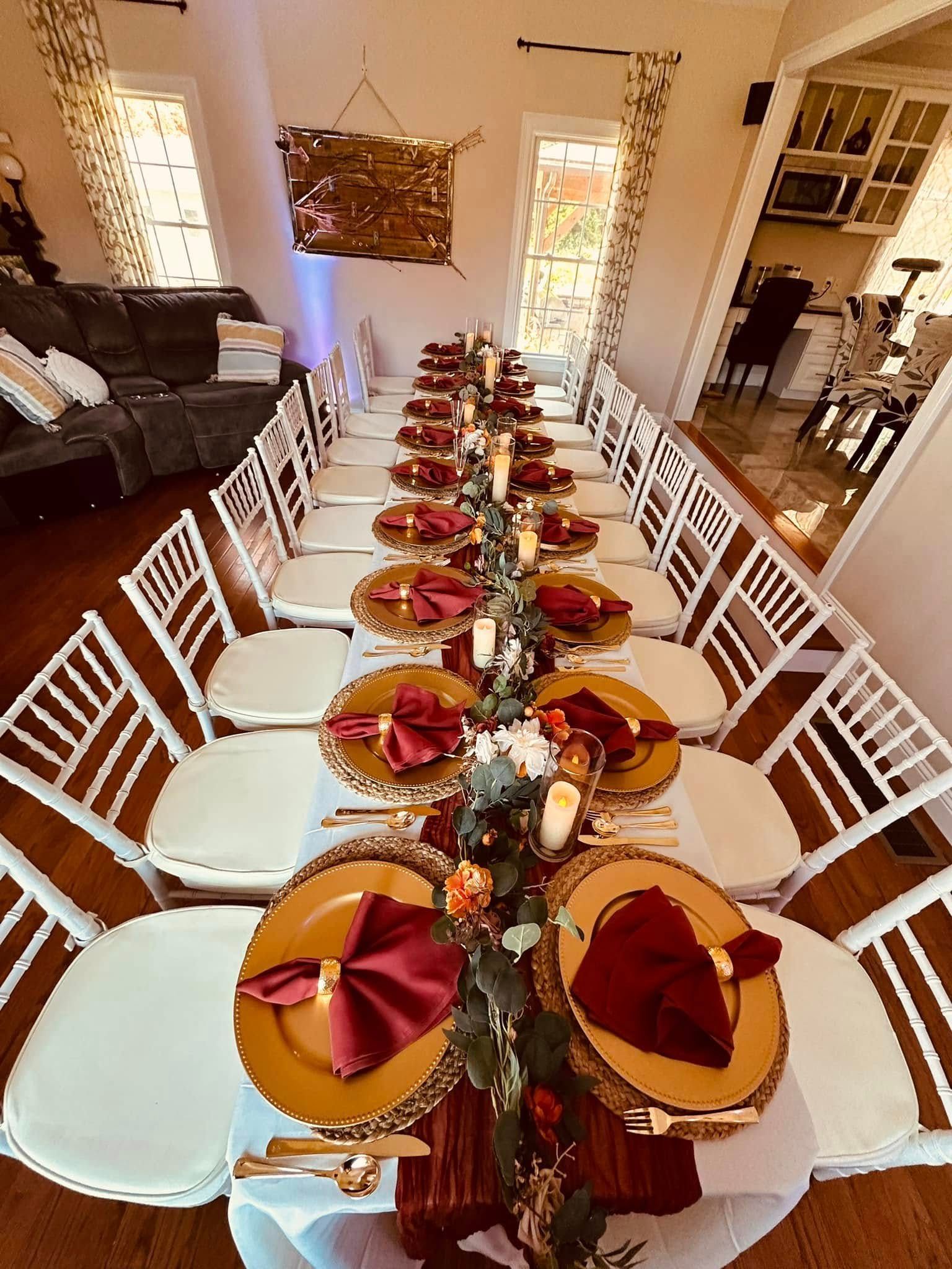 A long table with plates , napkins , and candles on it in a living room.