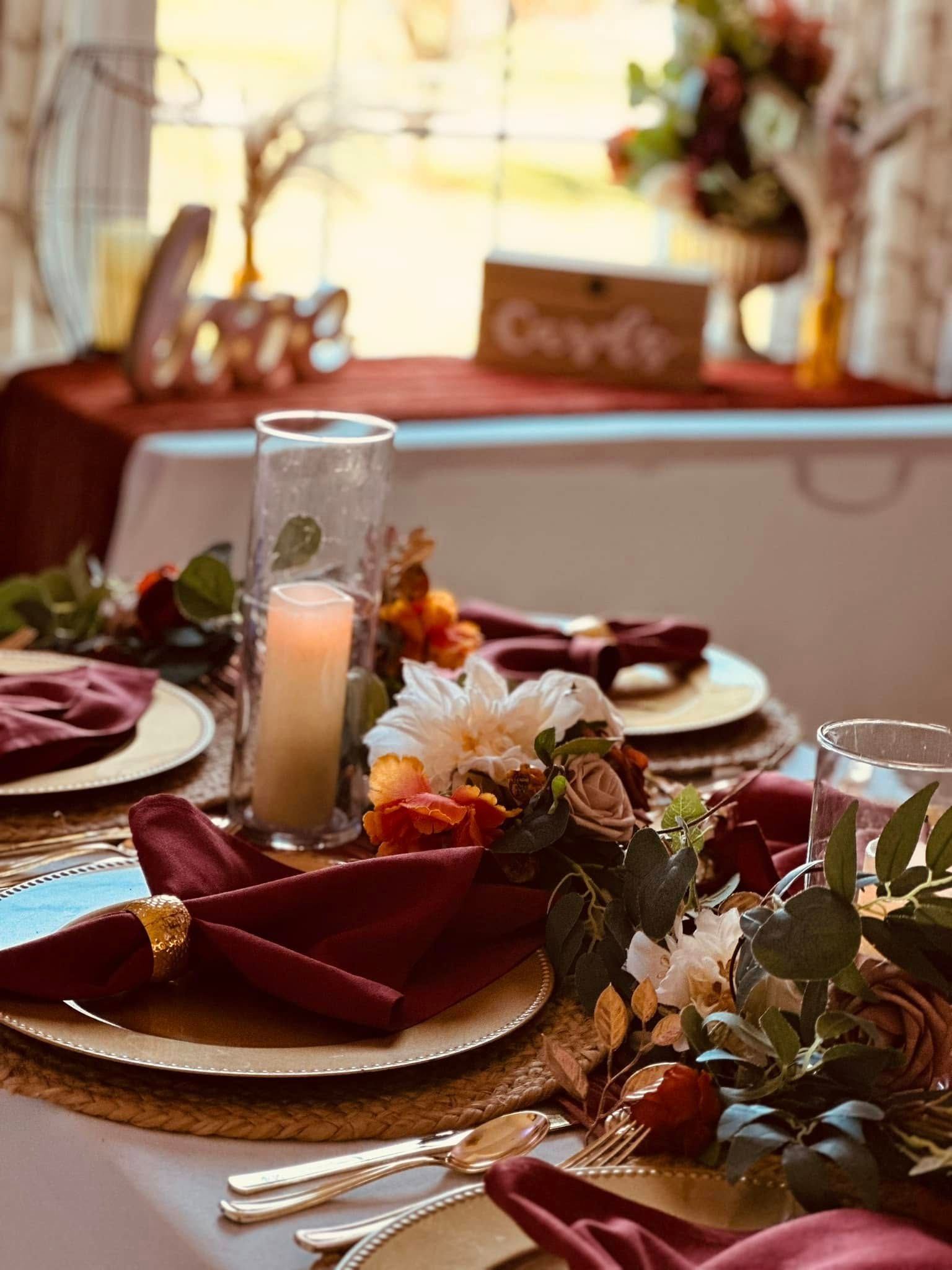 A table set for a wedding reception with plates , napkins , candles and flowers.