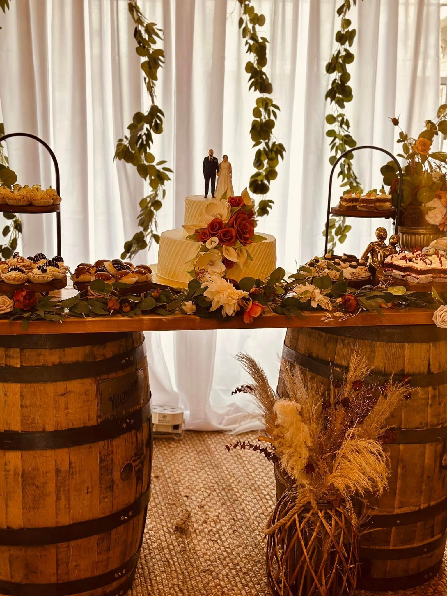 A table with two wooden barrels and a cake on it.