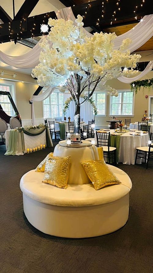 There is a tree in the middle of the room with tables and chairs.