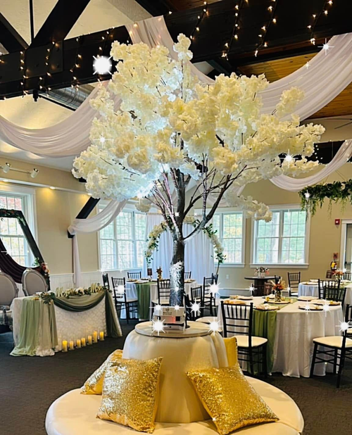 There is a tree in the middle of the room with tables and chairs.