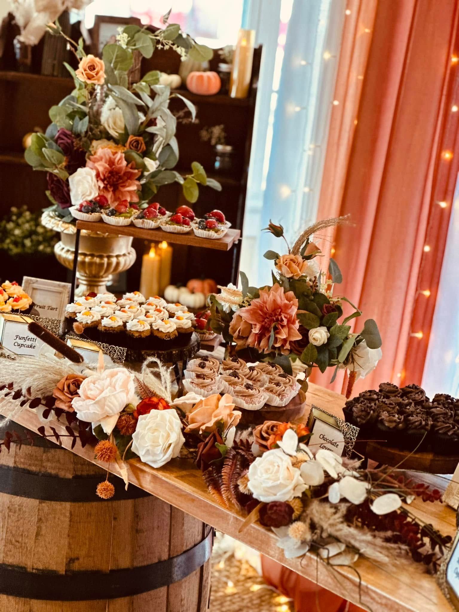 A wooden table topped with a variety of desserts and flowers.
