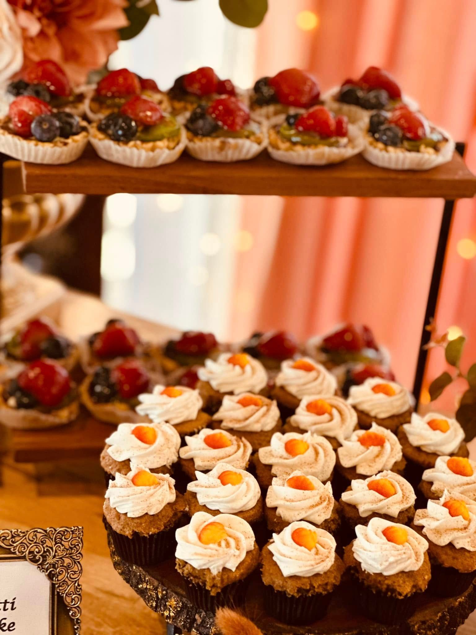 A table topped with cupcakes and fruit tarts.