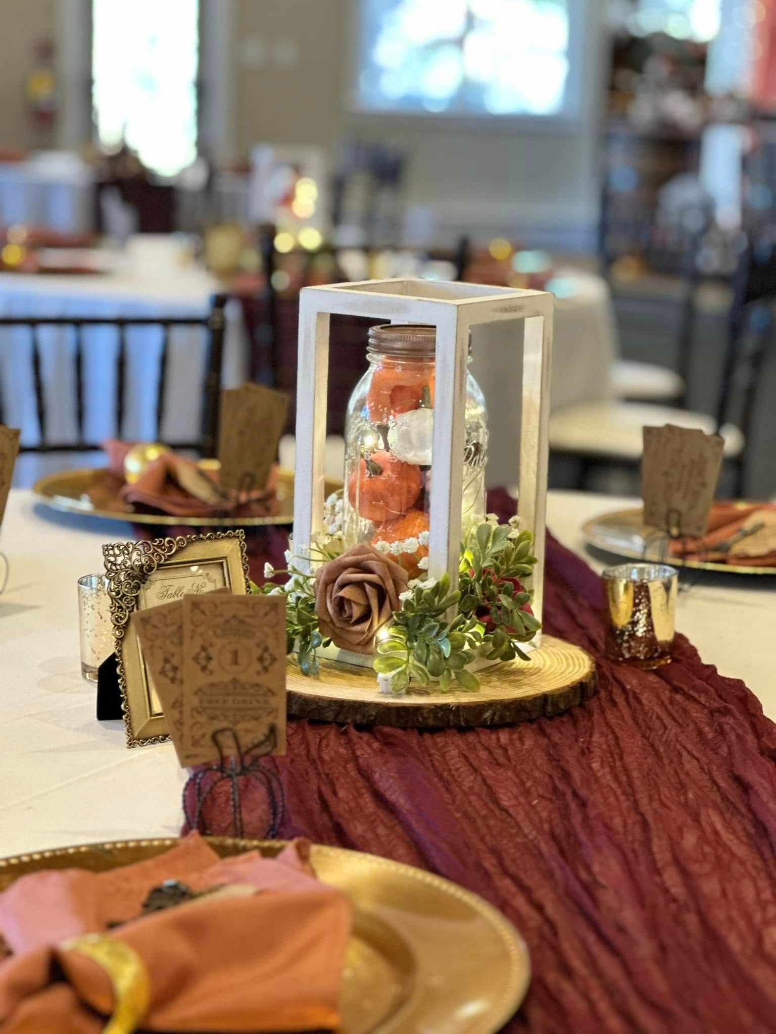 A table with plates , napkins , candles and a lantern on it.