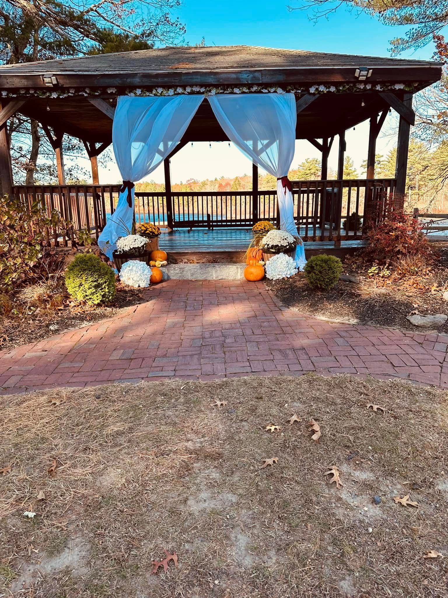 A gazebo is decorated for a wedding with pumpkins and flowers.