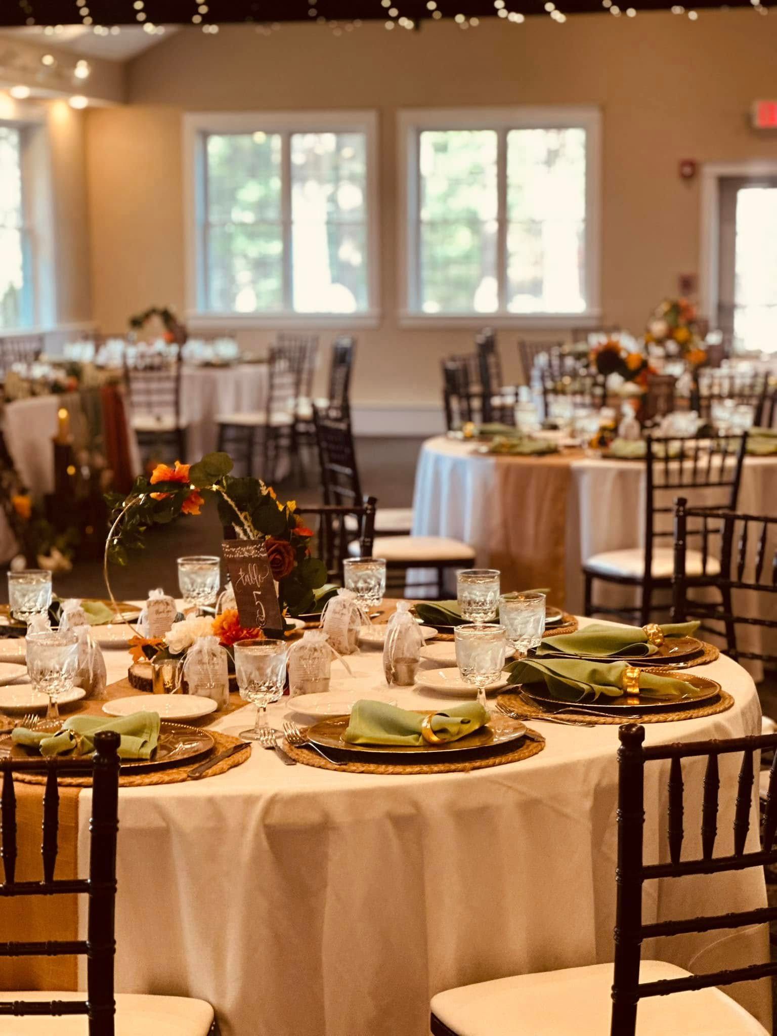 A room filled with tables and chairs set up for a wedding reception.
