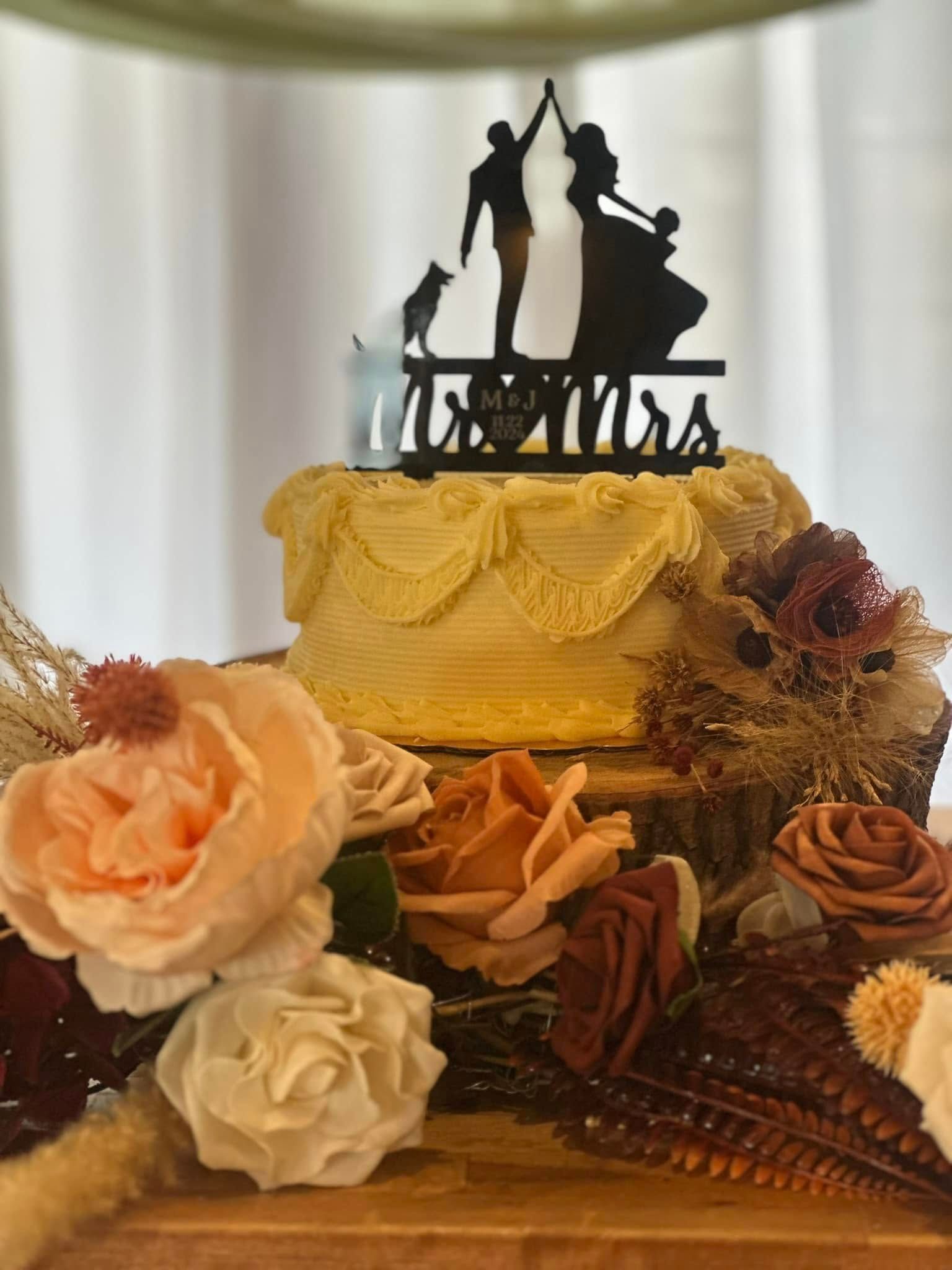 A wedding cake with a silhouette of a bride and groom and a child on top of it.