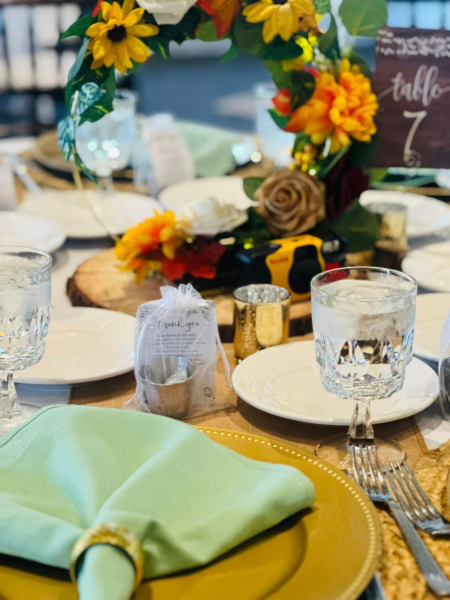 A table set for a wedding reception with plates , glasses , napkins and flowers.