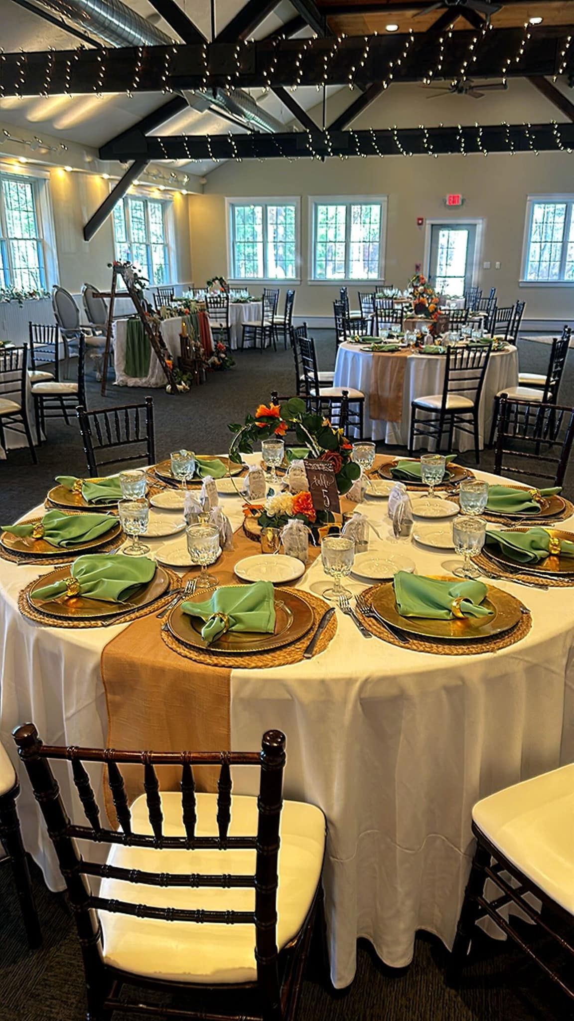 A large room with tables and chairs set up for a wedding reception.