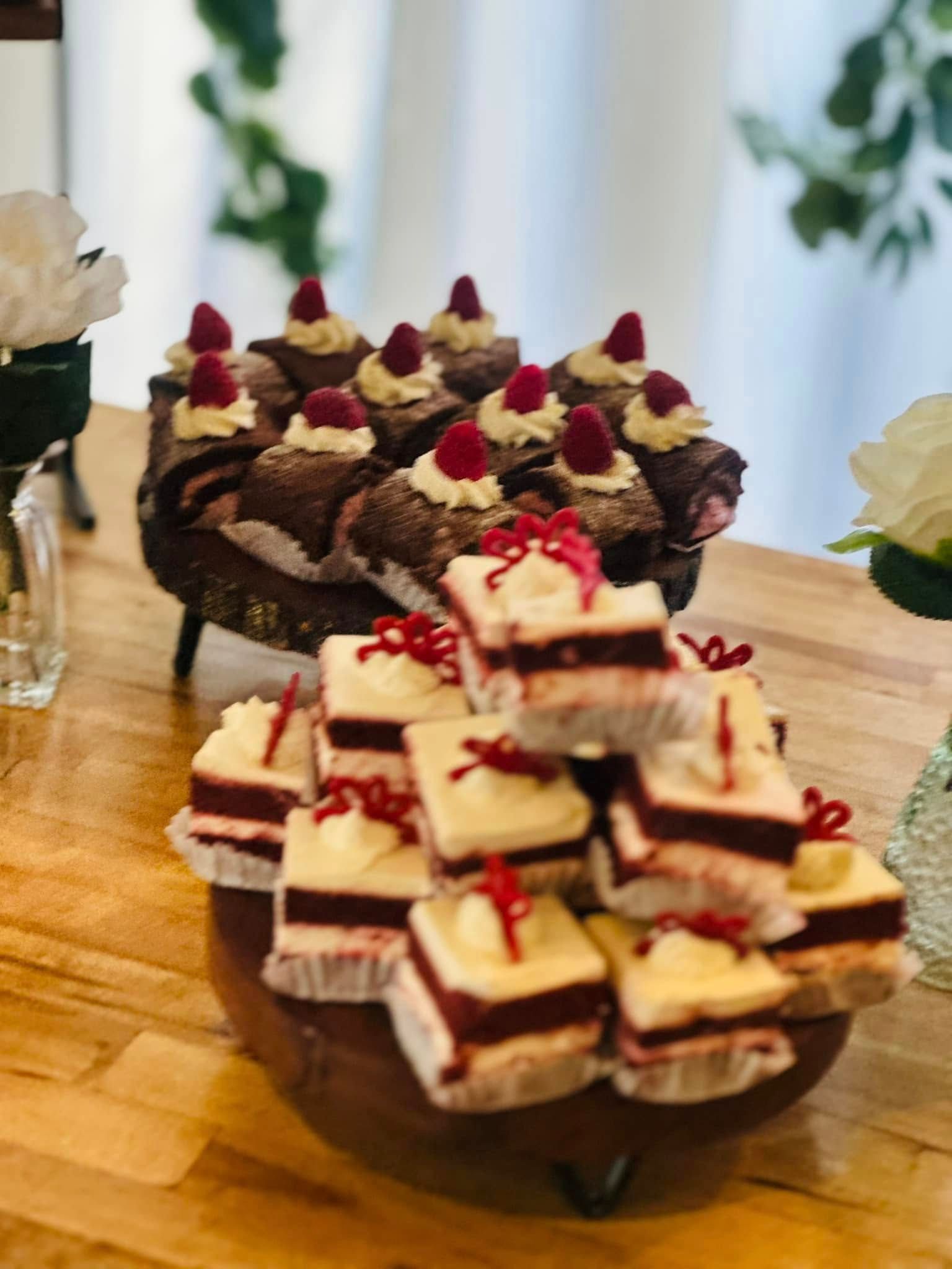 A bowl of cupcakes with raspberries on top on a wooden table.