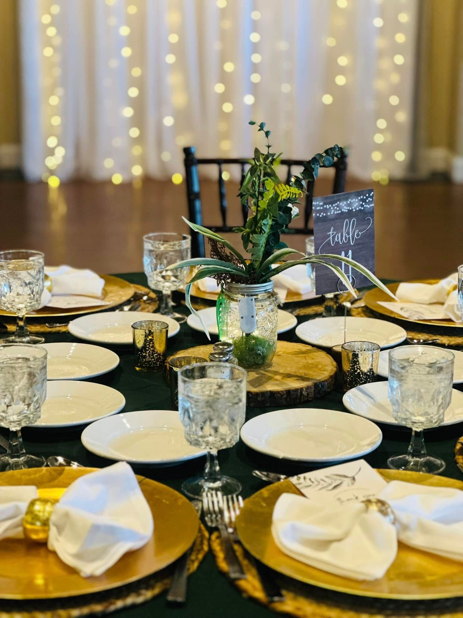 A table set for a wedding reception with plates , glasses , and napkins.