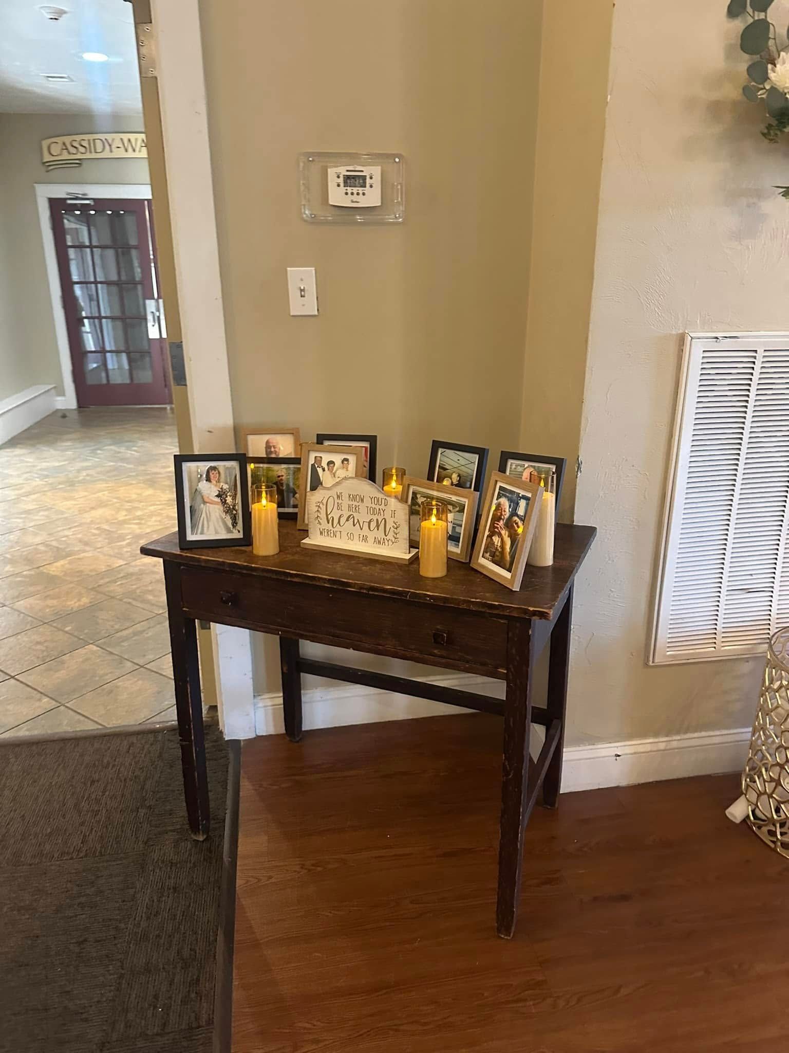 A table with pictures and candles on it in a living room.