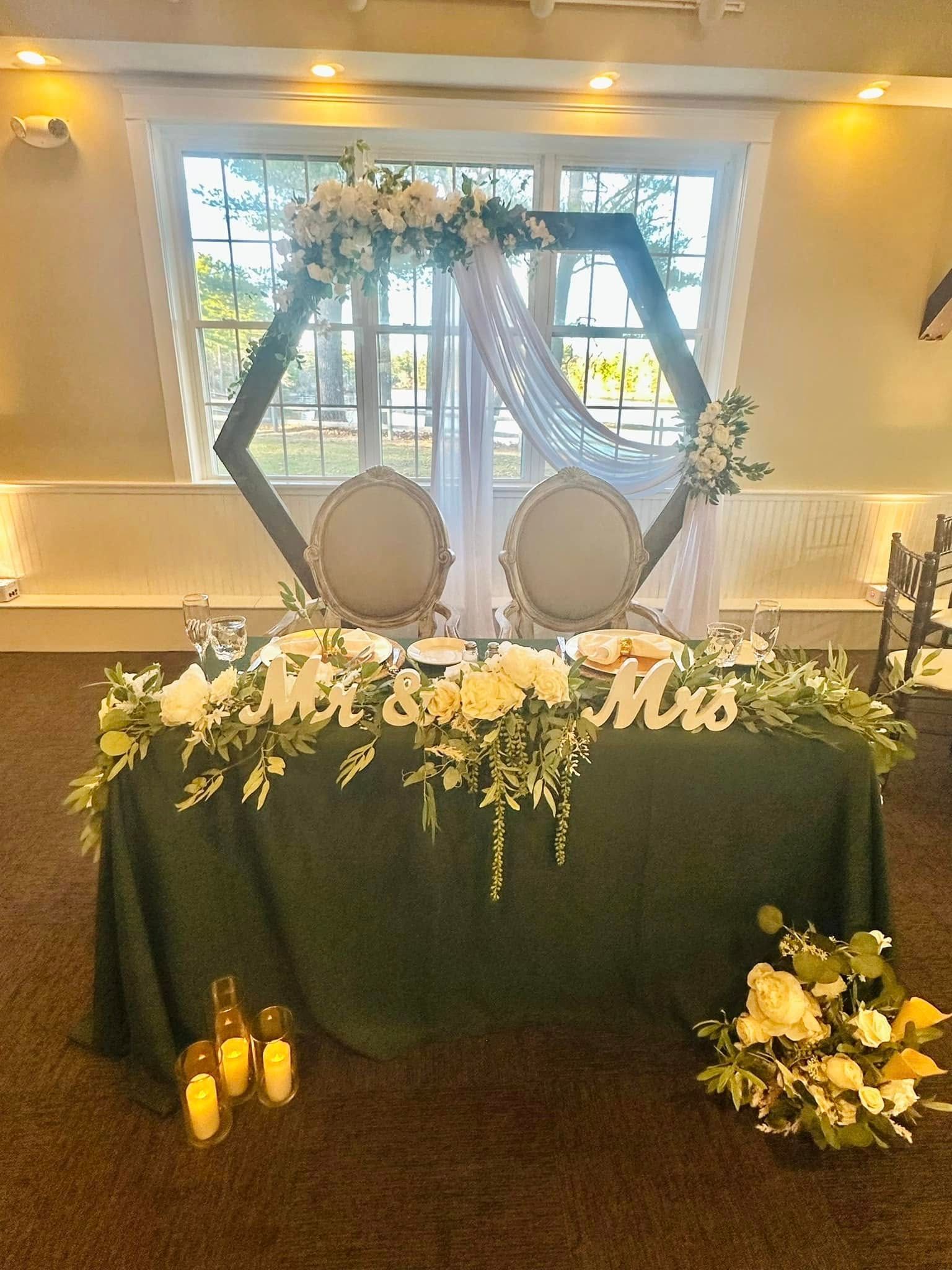 A bride and groom 's table is decorated with flowers and candles.