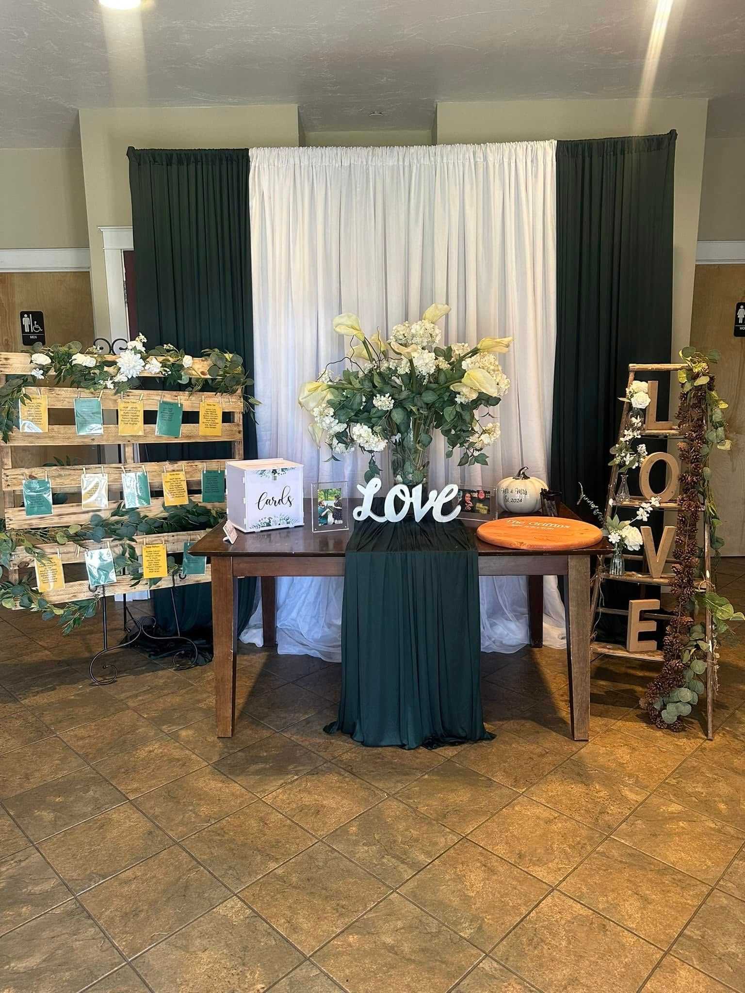 There is a table with flowers on it in front of a love sign.