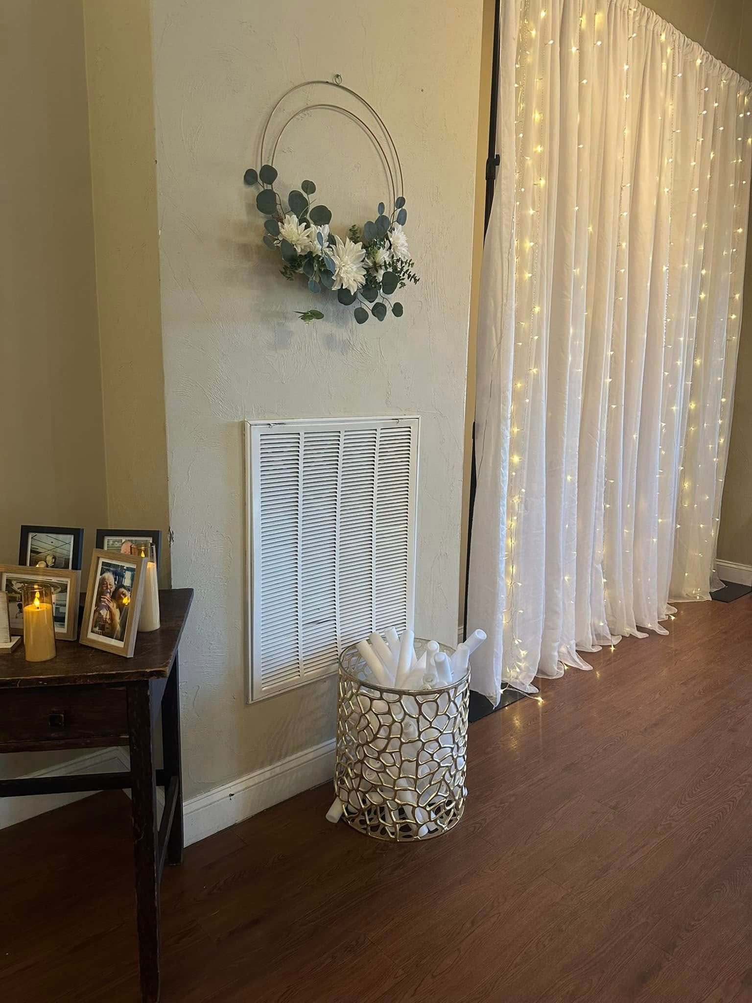 A room with a table , chairs , candles and a wreath on the wall.