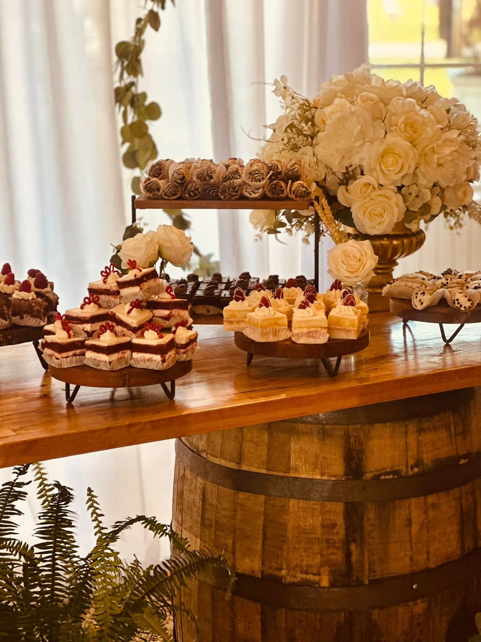 A wooden table topped with a variety of desserts and flowers.