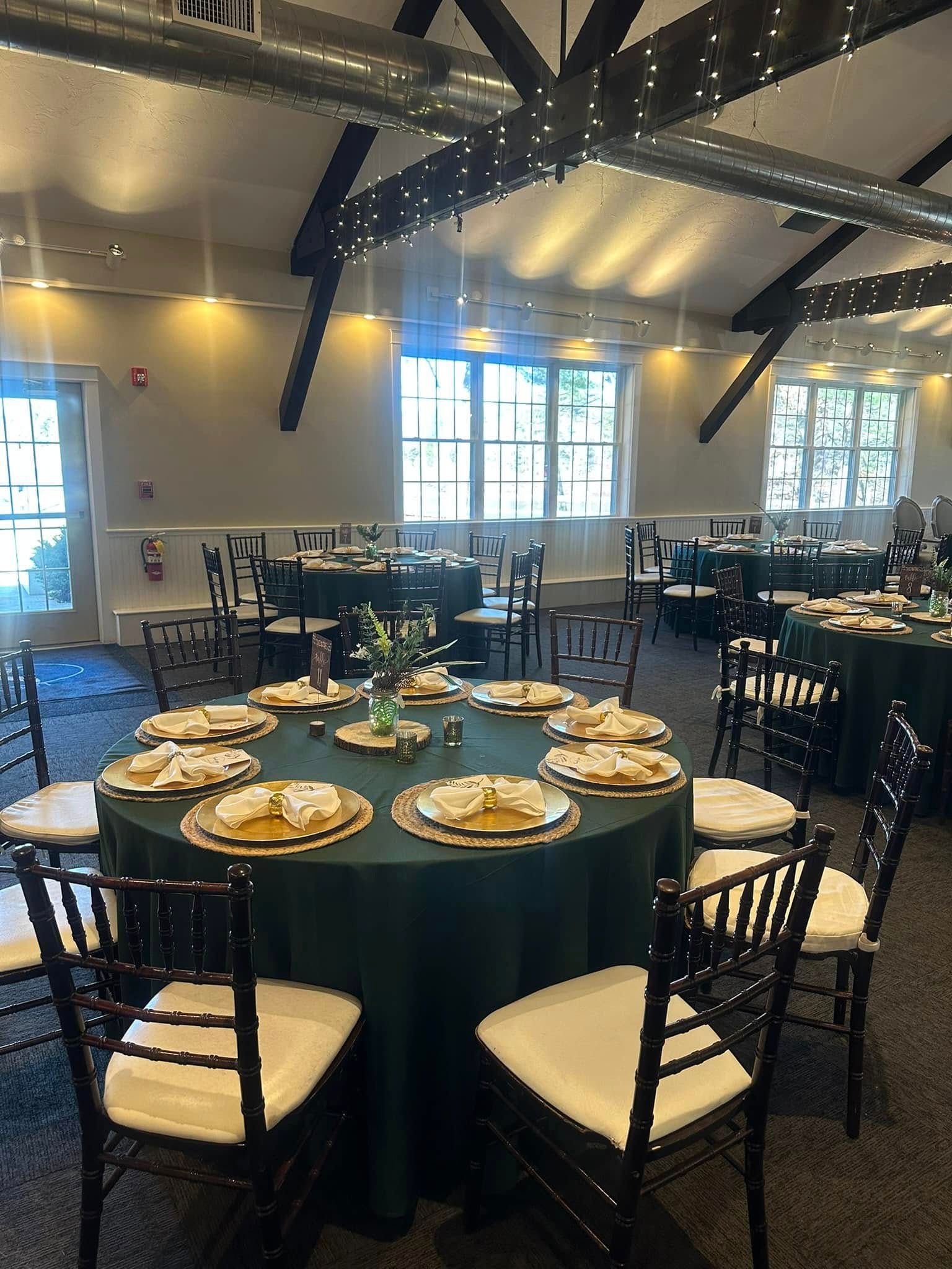 A large room with tables and chairs set up for a wedding reception.