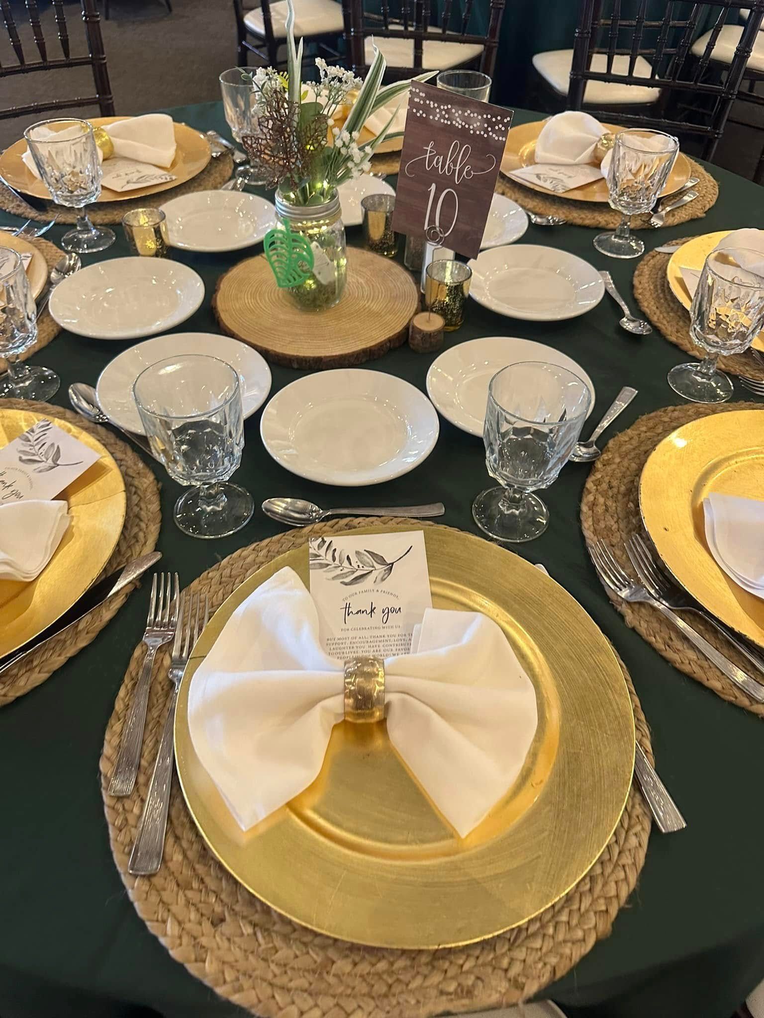 A table set for a wedding reception with plates , glasses , and napkins.