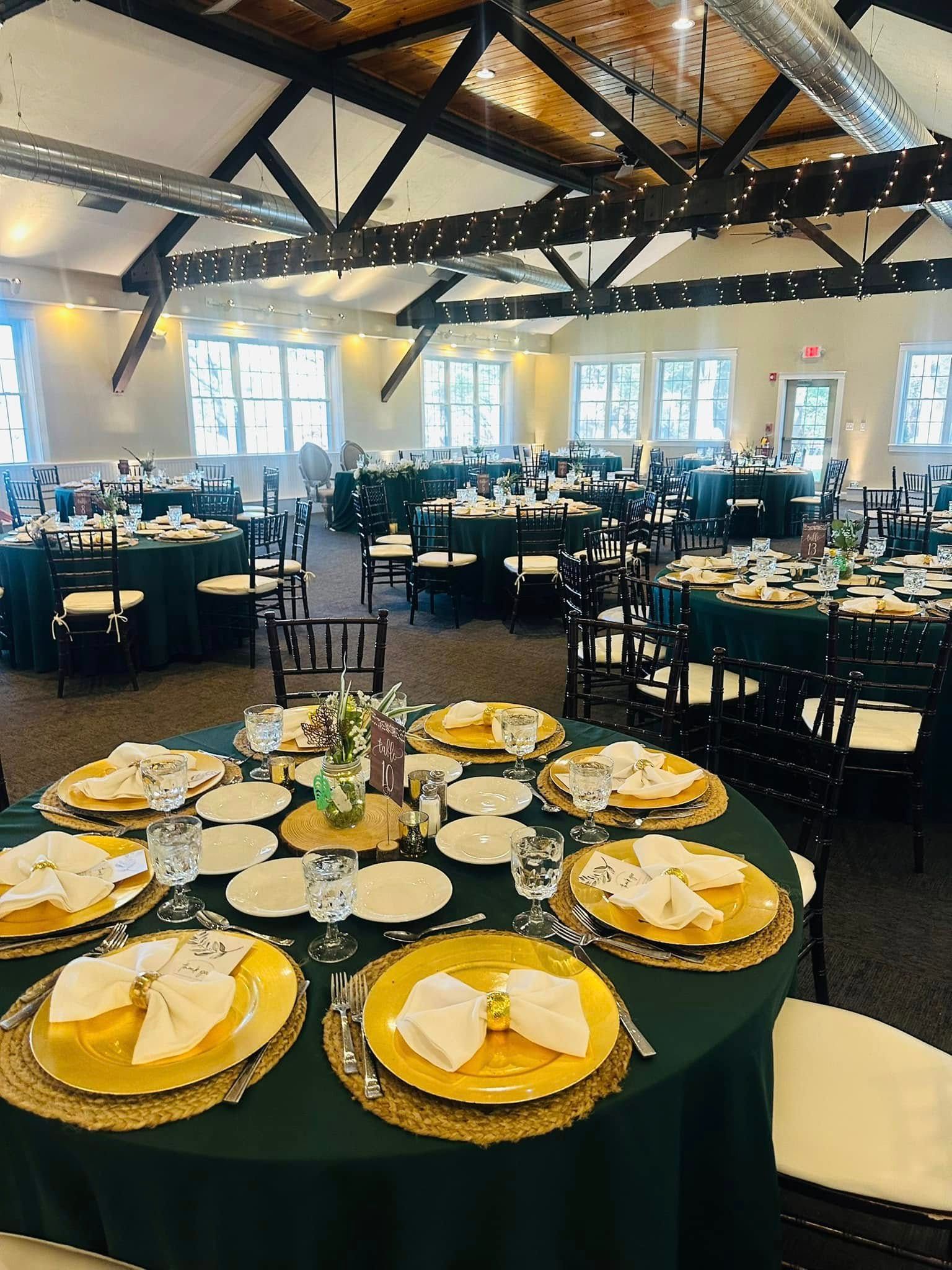 A large room filled with tables and chairs set up for a wedding reception.