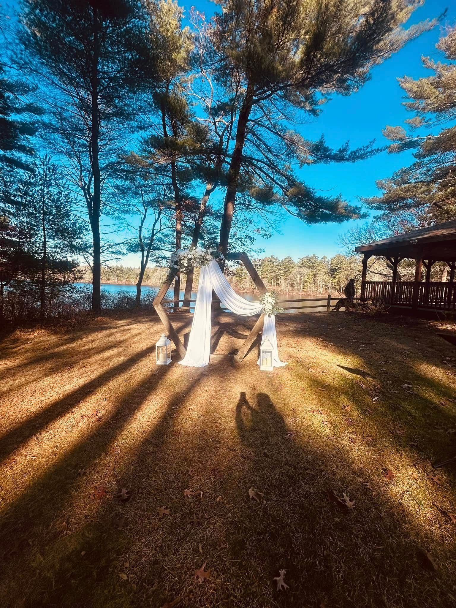 A person in a white dress is sitting under a tree in the woods.
