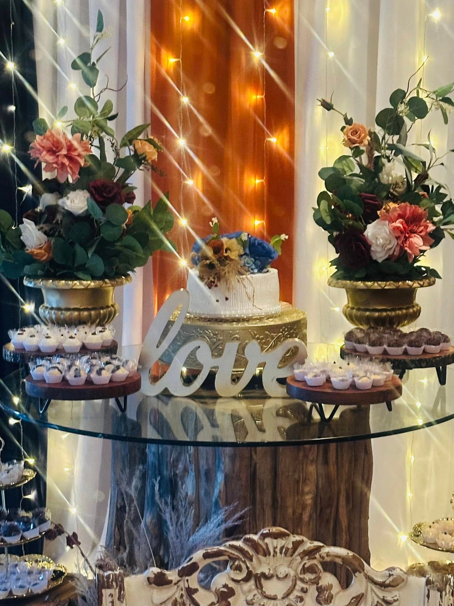 A table with a cake and flowers on it and a sign that says love.