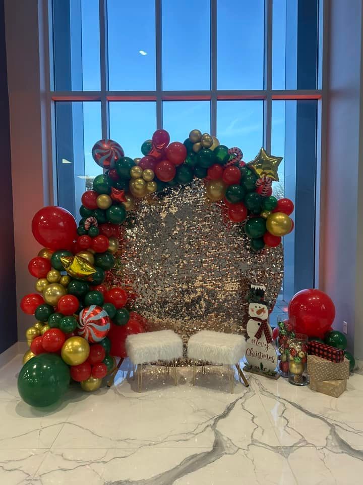 A christmas decoration with balloons and a snowman in front of a window.