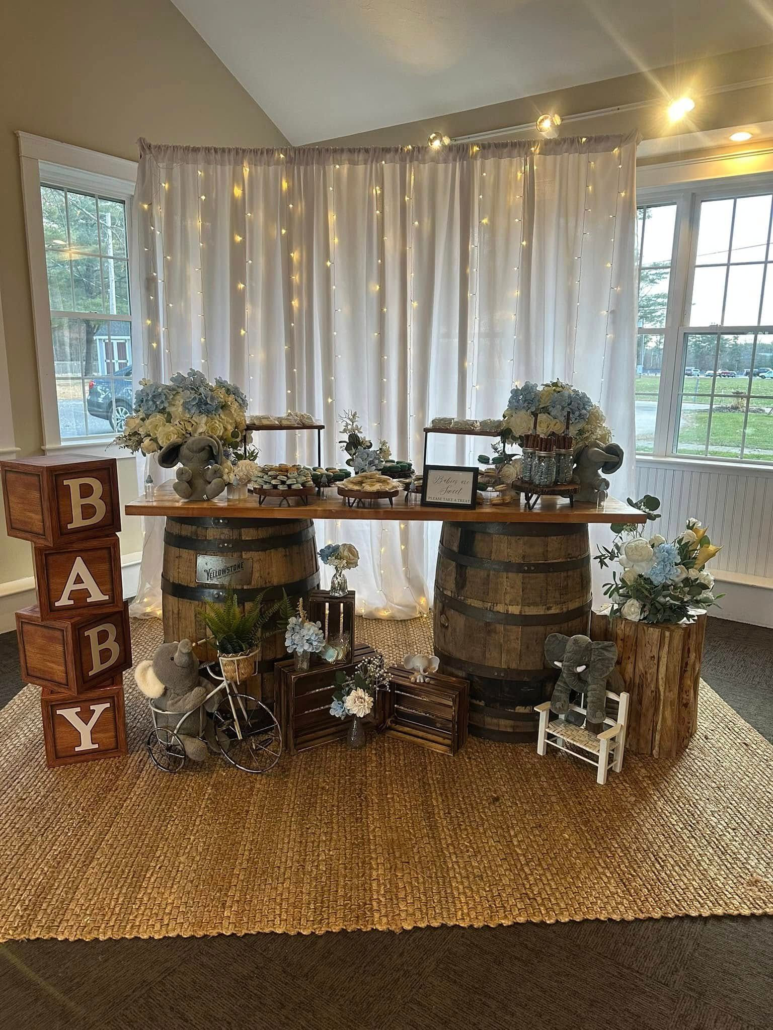 A baby shower table decorated with wooden barrels and wooden blocks.