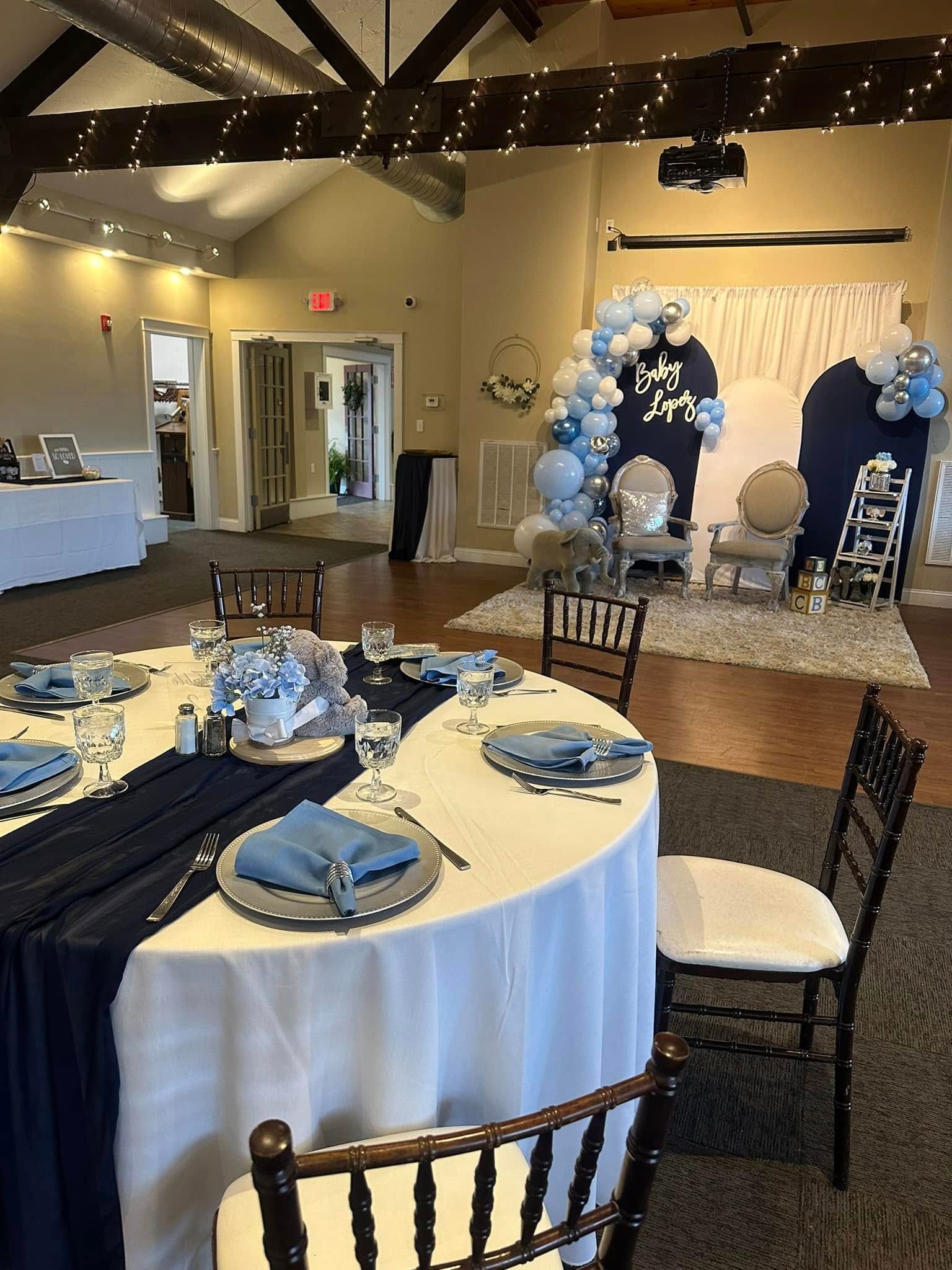 A room with tables and chairs set up for a baby shower.