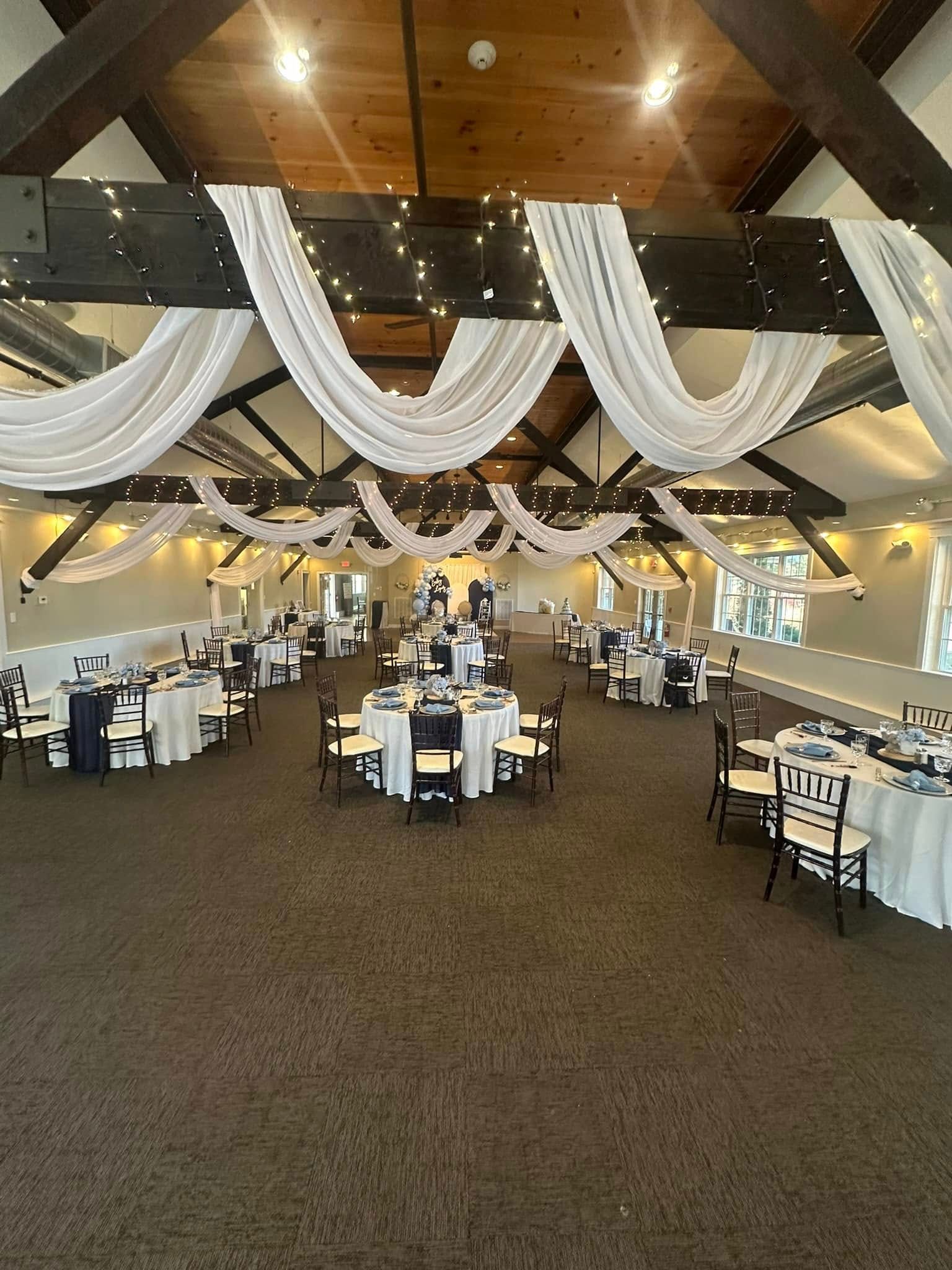 A large room with tables and chairs set up for a wedding reception.