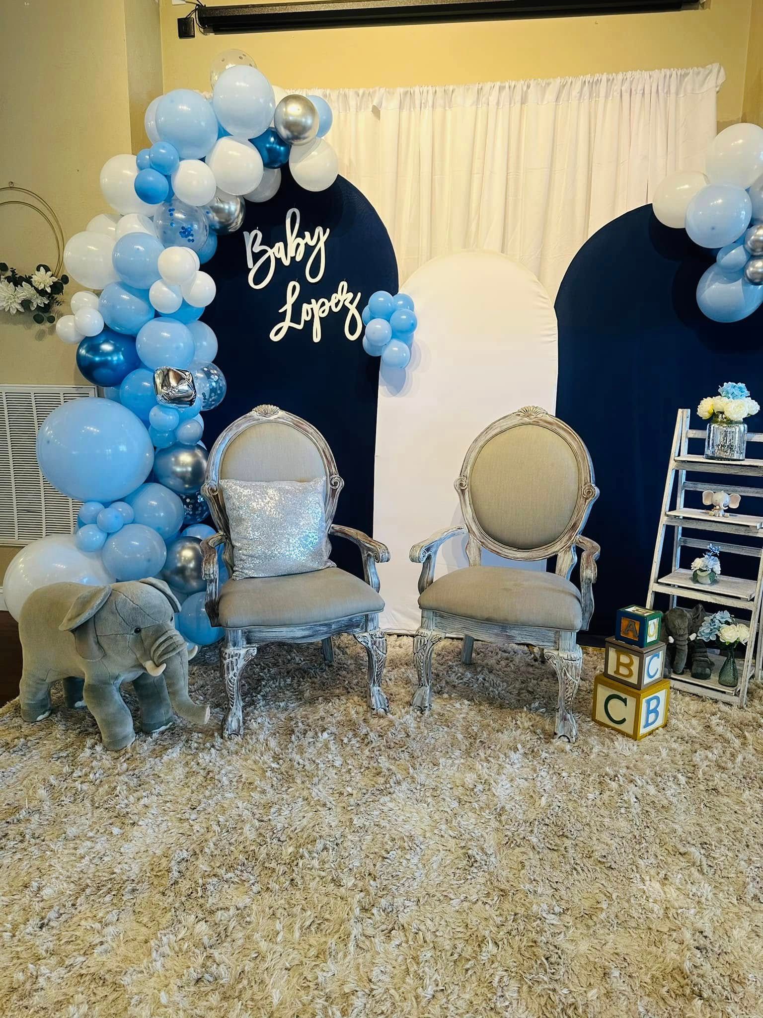 A room decorated with balloons , chairs , and a stuffed elephant.