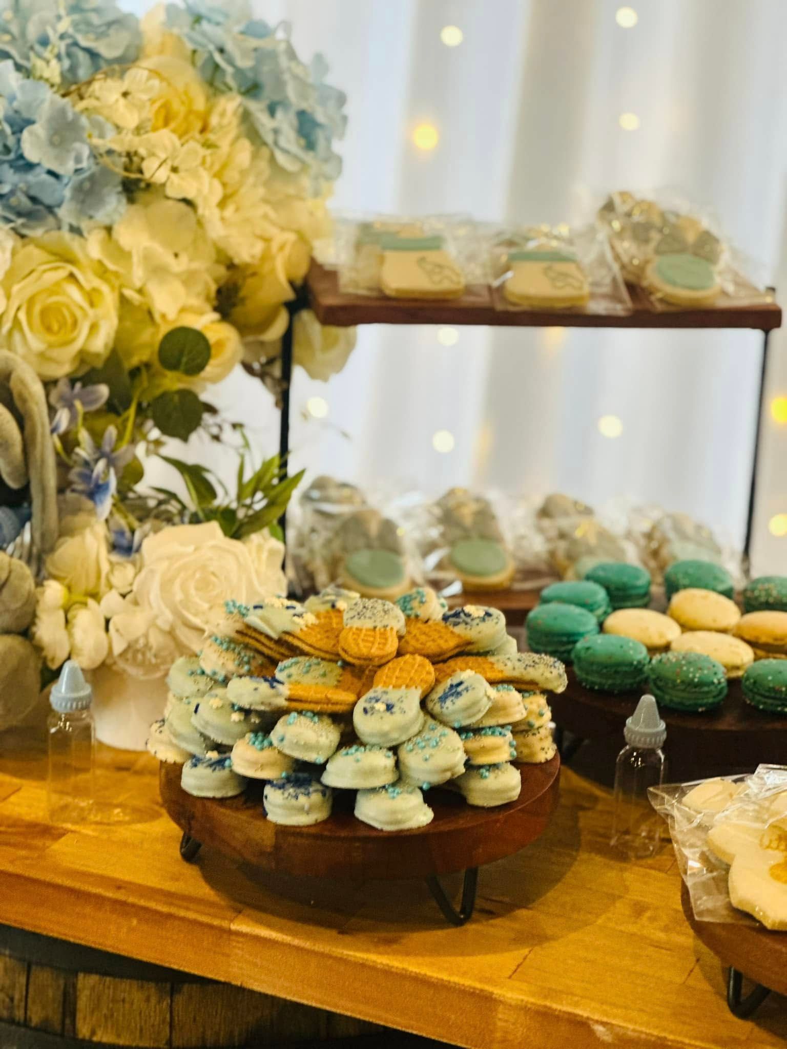 A table topped with cupcakes , cookies , and flowers.