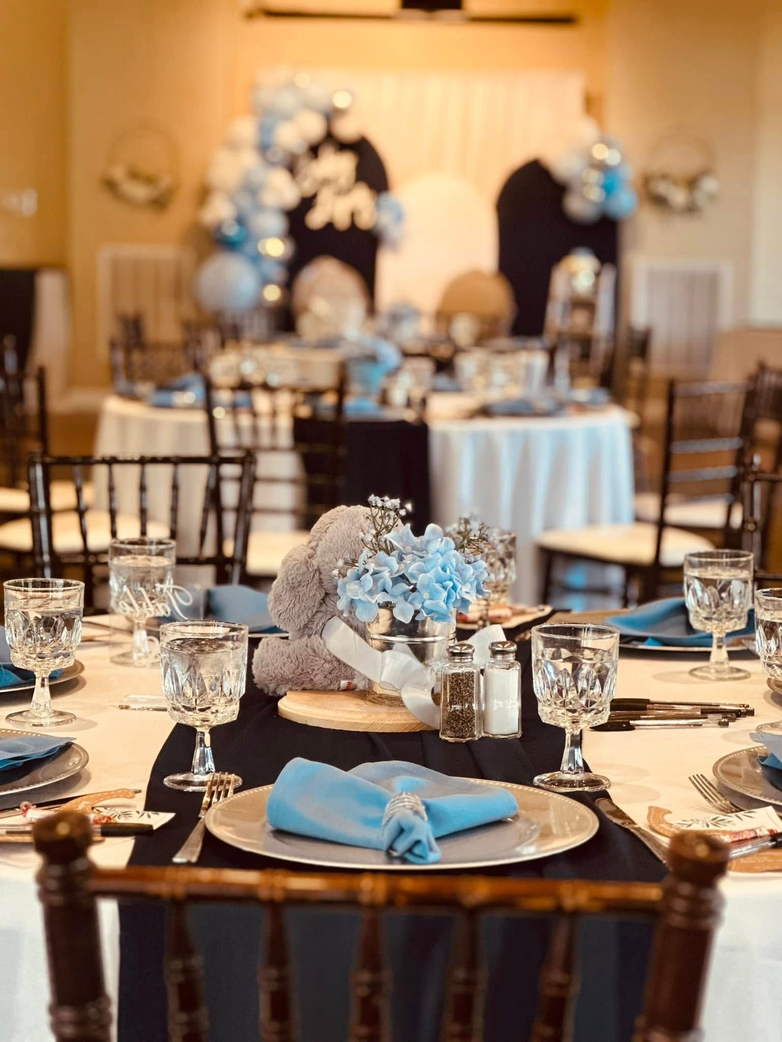 A table set for a baby shower with a teddy bear in the middle.