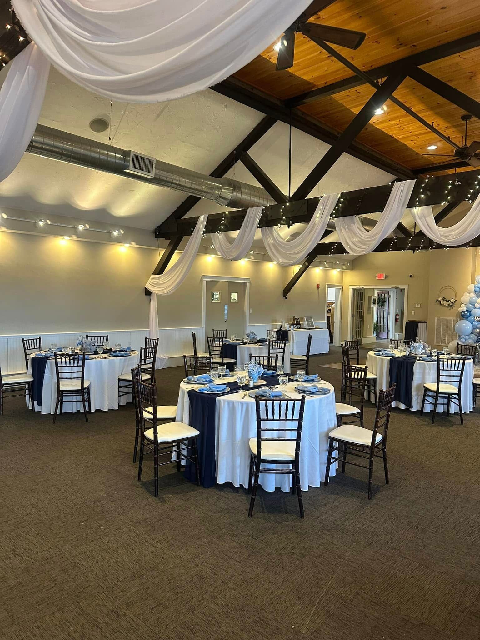 A large room with tables and chairs set up for a wedding reception.