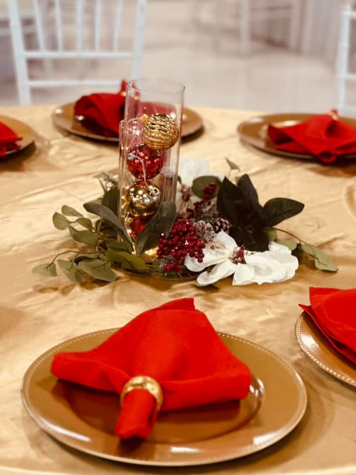A table with plates , napkins and a vase of flowers on it.